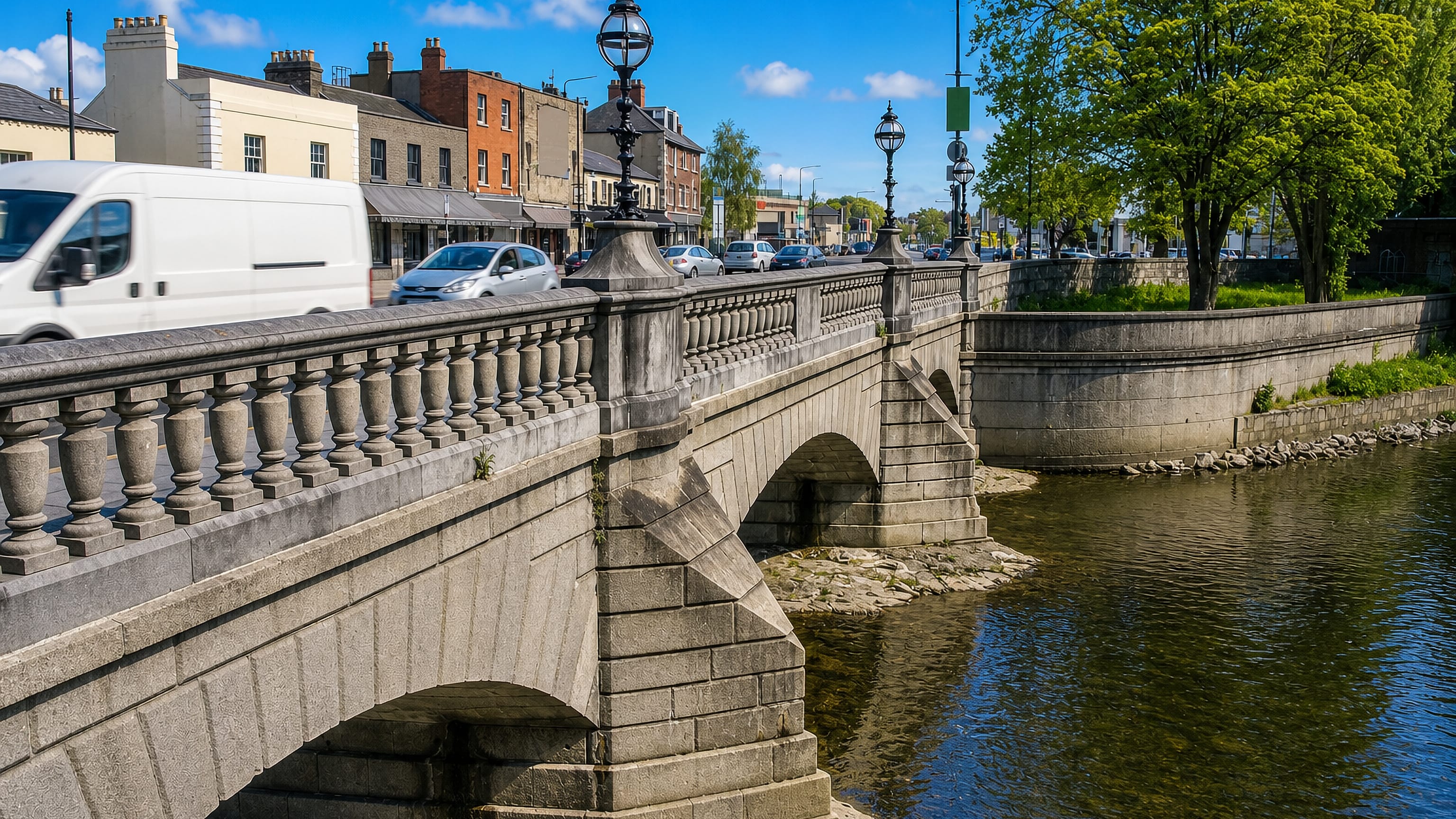 Stone-arched bridge over the River Dodder in Ballsbridge, Dublin, with Victorian lamp standards and shopfronts