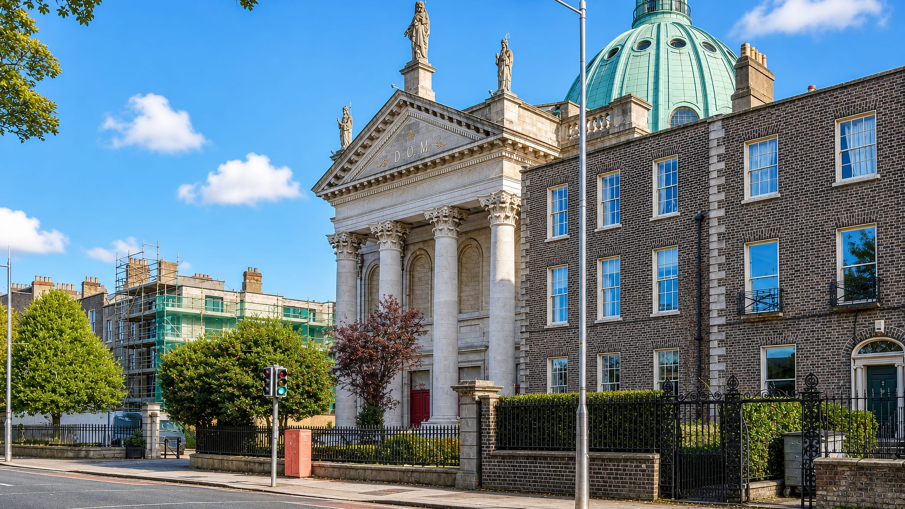 The green copper dome and stone portico of Rathmines' church beside a Georgian brick terrace, Dublin.