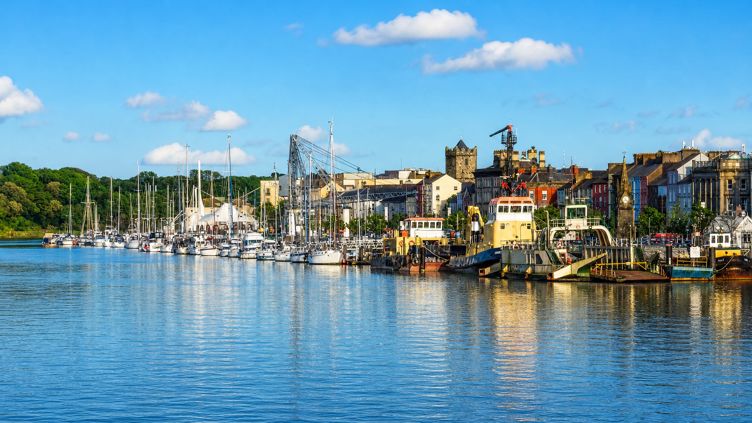 Waterford's quays on the River Suir with Reginald's Tower, the Clock Tower and moored boats along the waterfront