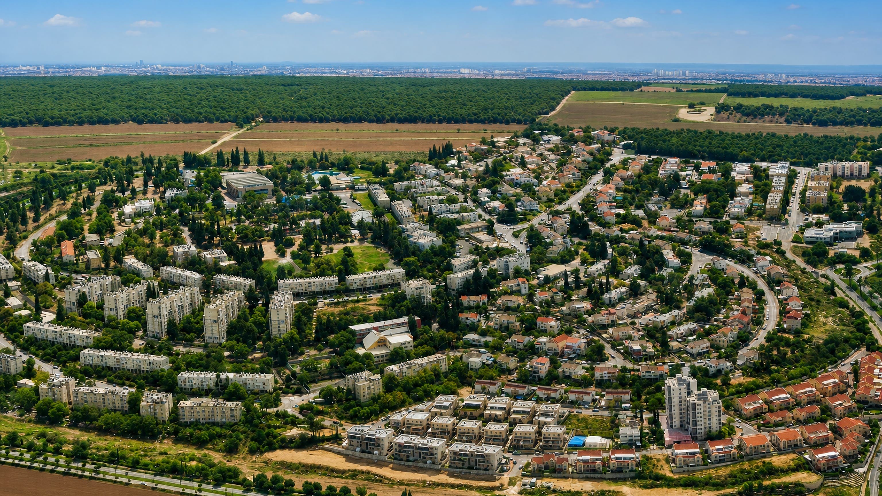 Aerial view of Qiryat Ata, Israel, its apartment blocks and tile-roofed houses ringed by forest and fields