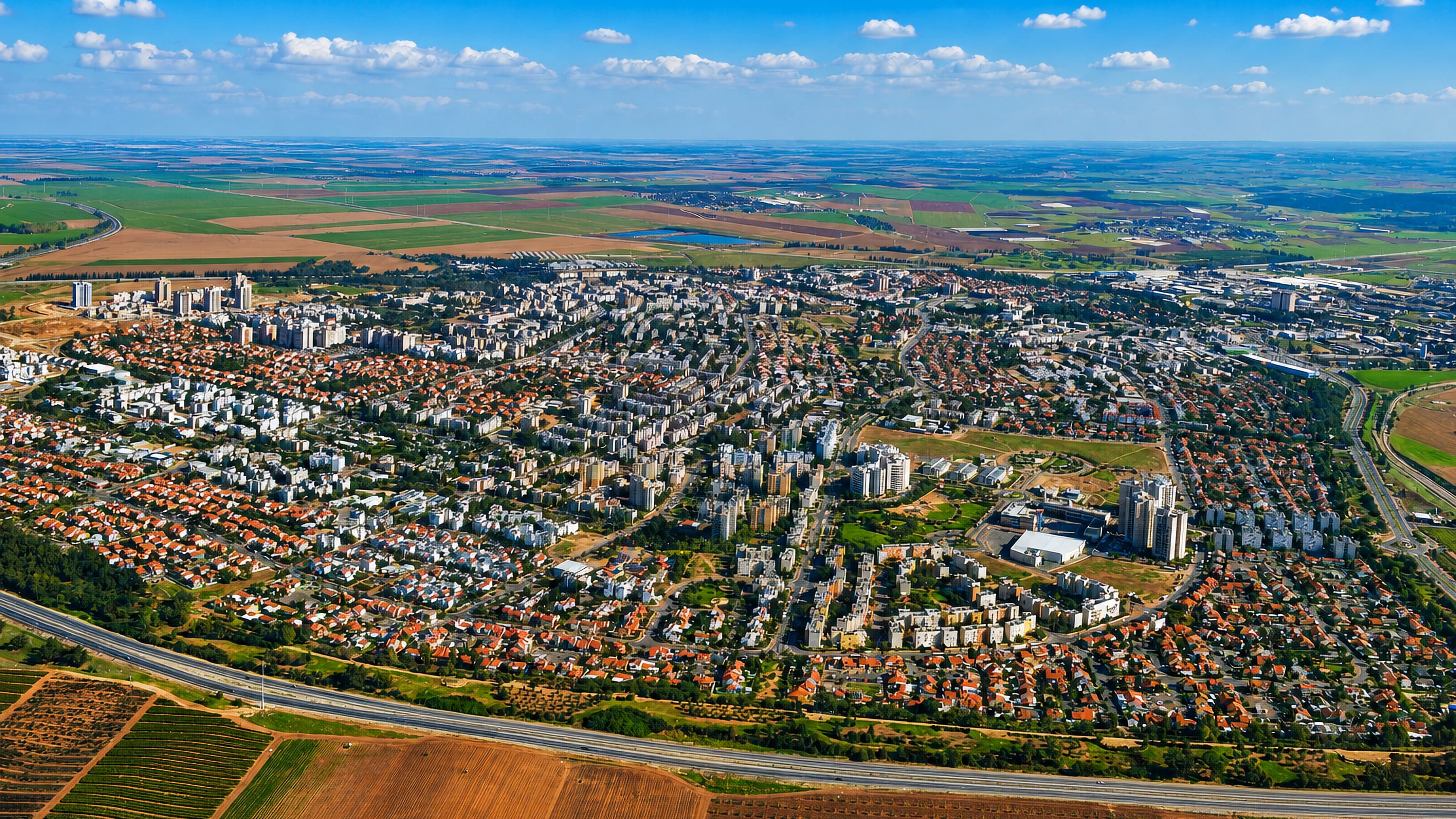 Aerial view of Kiryat Gat, Israel, its apartment blocks and red-roofed homes ringed by open farmland.