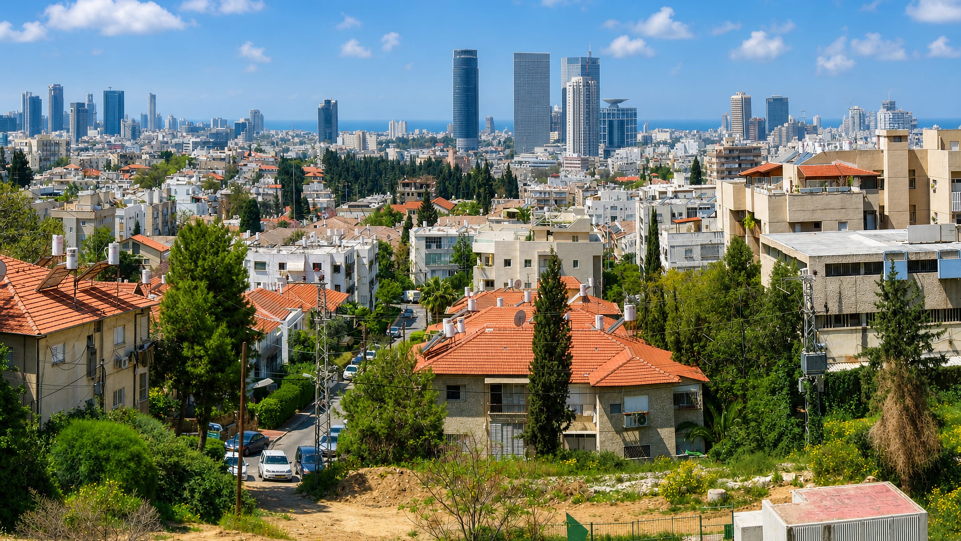 Red-roofed hillside homes in Givatayim, Israel, looking across to the Tel Aviv high-rise skyline and the sea.
