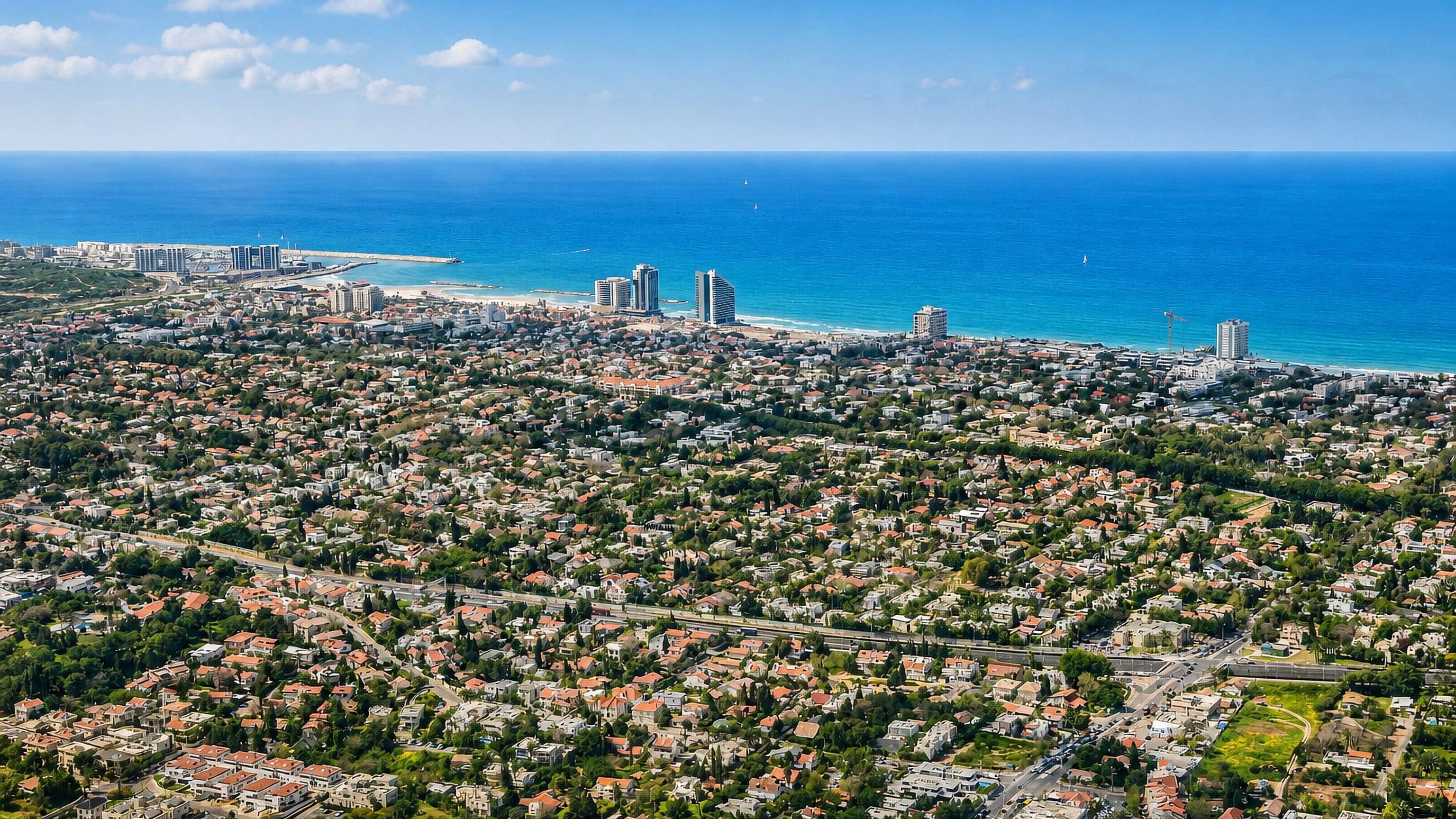 Aerial view of Herzliya, Israel, with its marina, seafront towers and leafy villa streets along the Mediterranean.