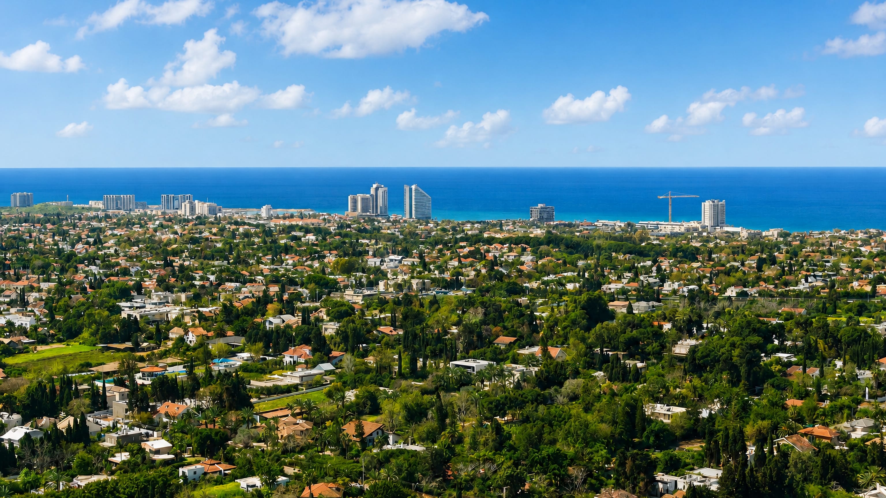 Herzliya Pituah's leafy villa districts spreading to the Mediterranean, with hotel towers on the shoreline.