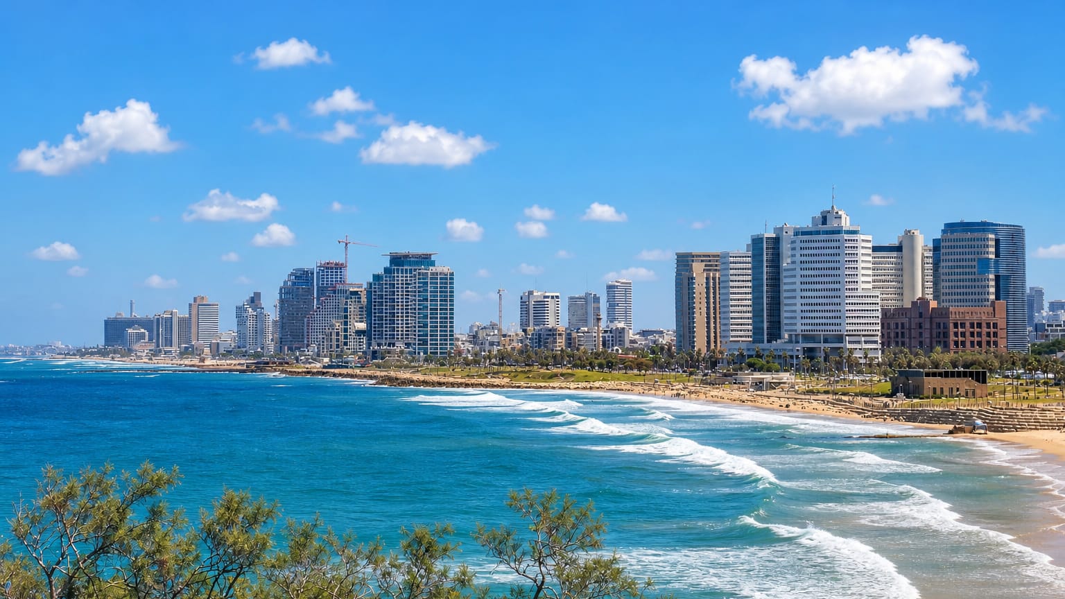 Tel Aviv beachfront skyline of high-rise towers above the Mediterranean shore with waves rolling onto the sand.