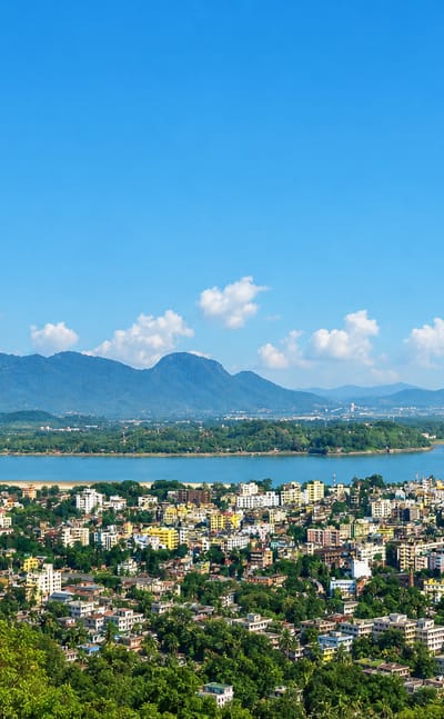 Guwahati spreading along the wide Brahmaputra River below forested hills in Assam, India.