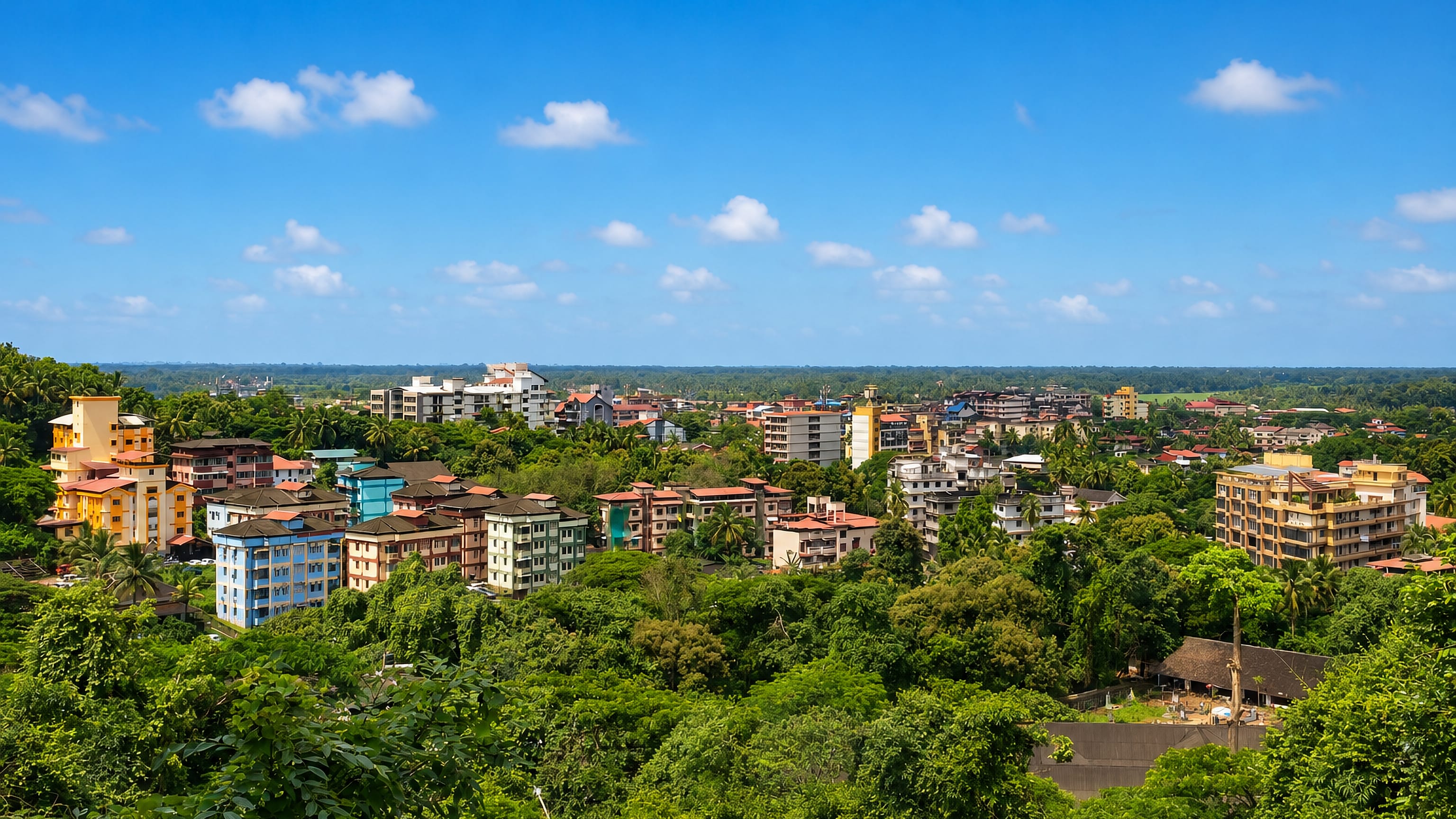 Colourful low-rise buildings among dense palms and greenery in Madgaon (Margao), Goa, India