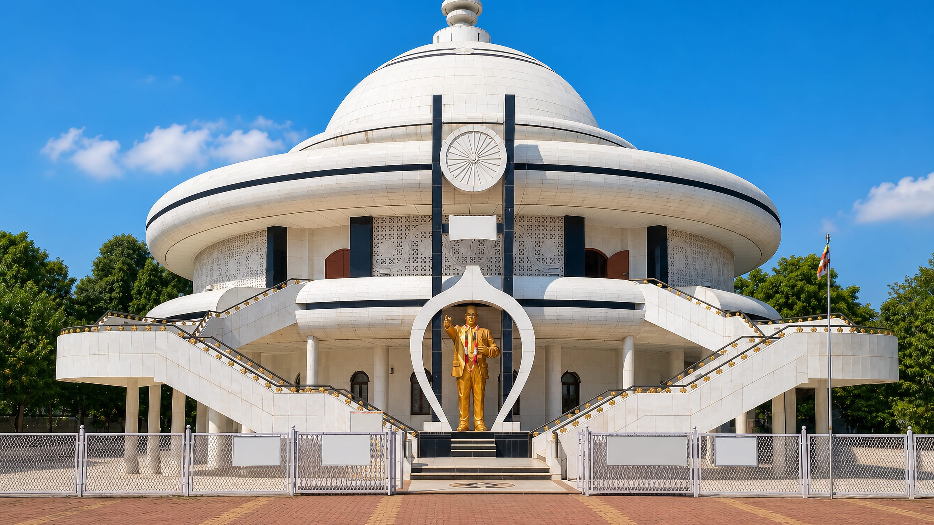 White domed Ambedkar memorial with a golden statue and brick forecourt at Mhow, Madhya Pradesh.