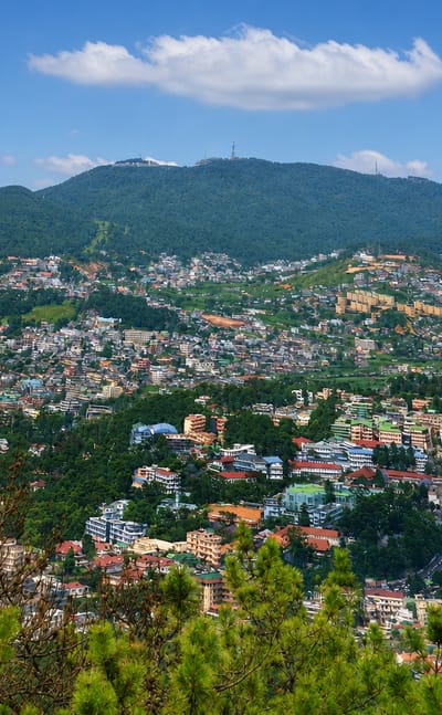 Hillside townscape of Shillong, India, with dense houses climbing forested Meghalaya hills