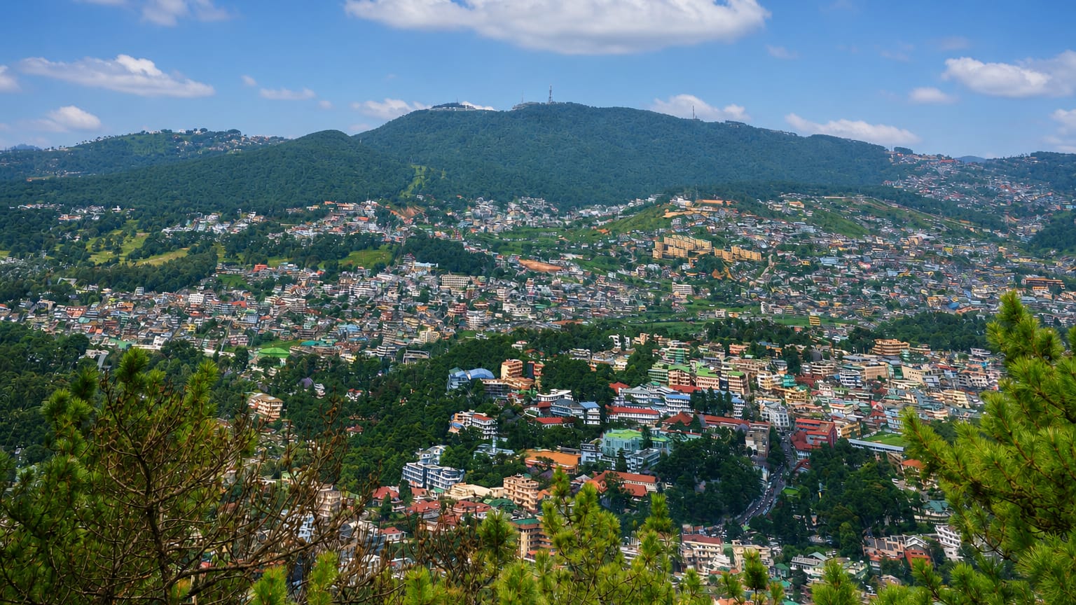 Hillside townscape of Shillong, India, with dense houses climbing forested Meghalaya hills