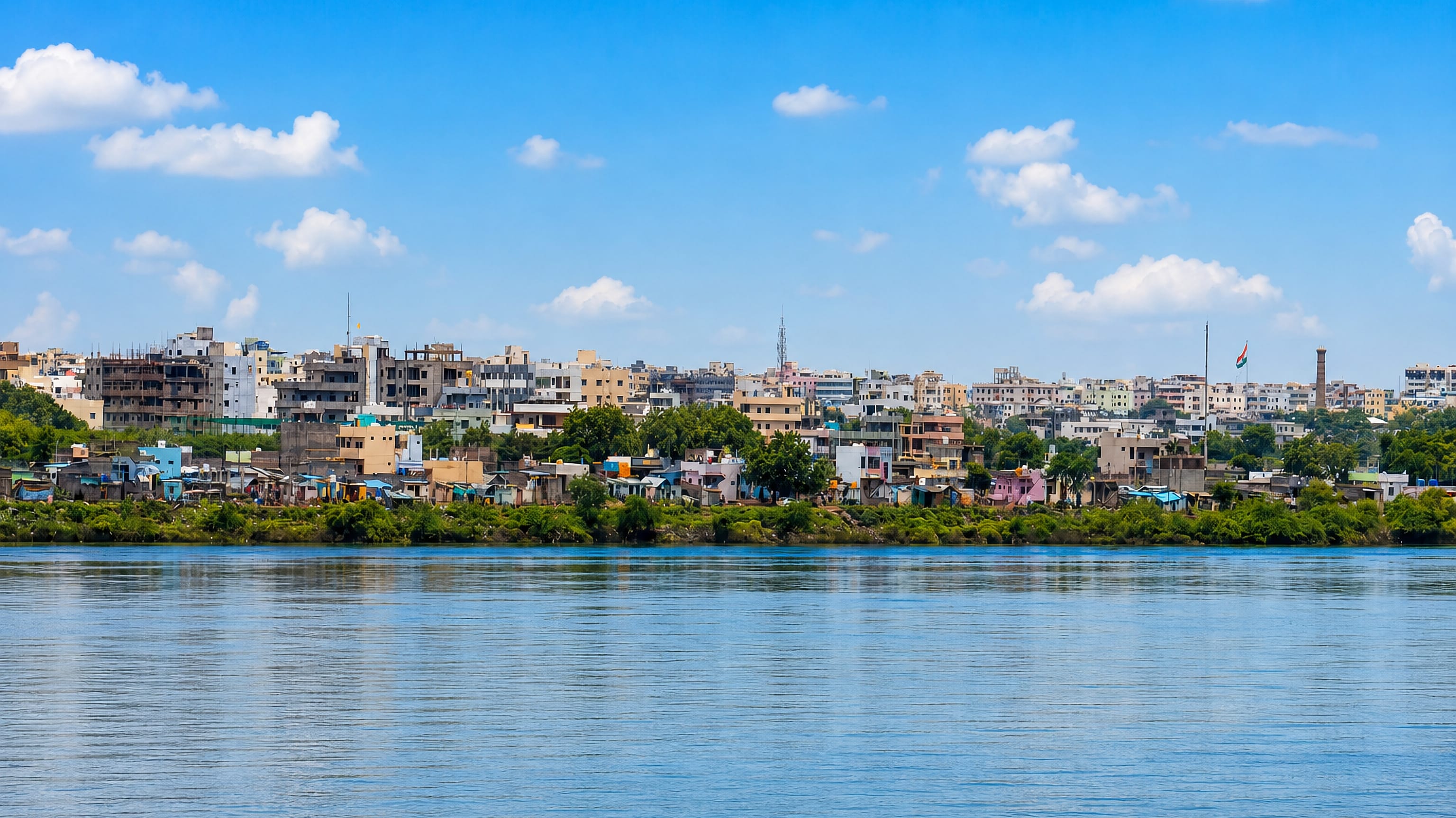 Kurnool's riverfront rooftops and concrete blocks seen across a wide river in Andhra Pradesh, India.