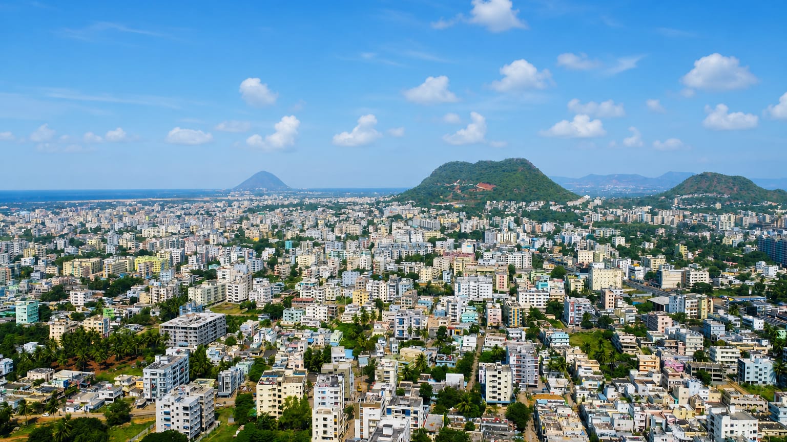 Aerial view of Visakhapatnam, India, a dense mid-rise city among green hills beside the sea