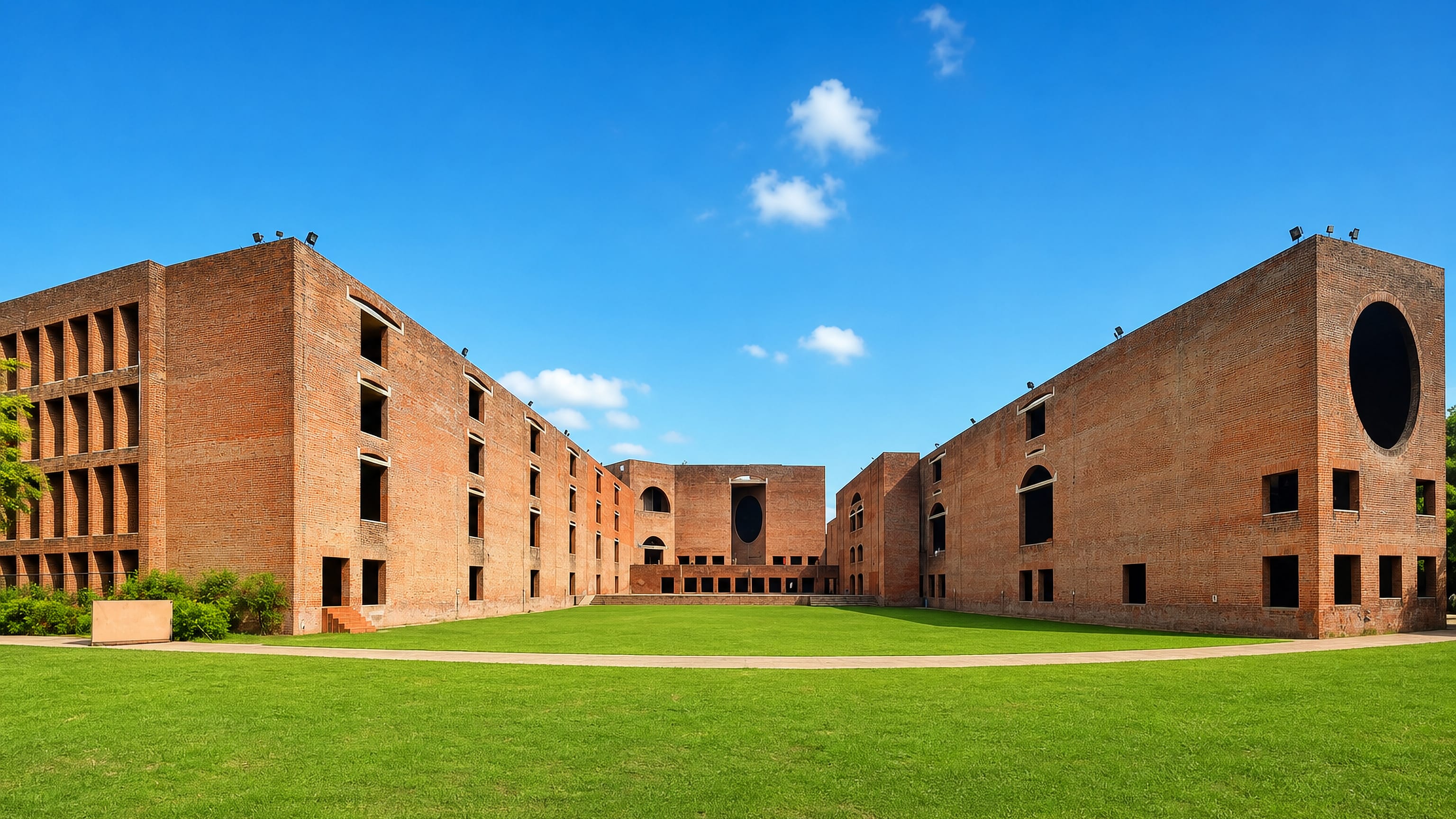 The brick arcades of the IIM Ahmedabad campus in Ahmedabad's West Zone, seen across a green lawn