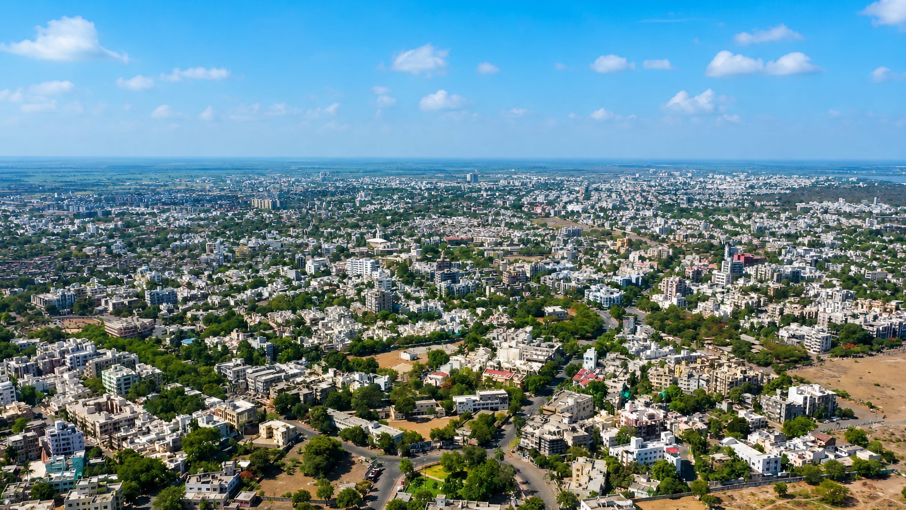 Wide aerial view of Bhavnagar, India, showing dense low-rise white housing spreading to a flat hazy horizon.