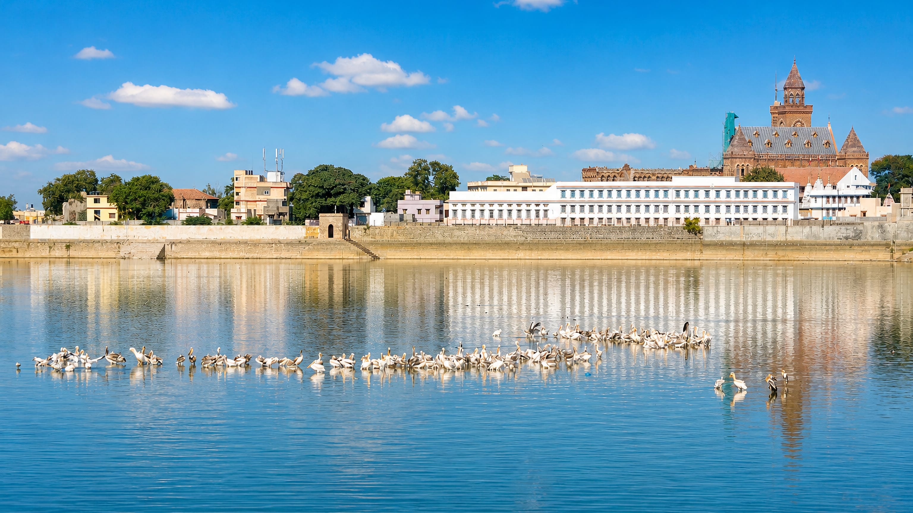 Hamirsar Lake in Bhuj with pelicans on the water and the Gothic tower of Prag Mahal on the far bank.
