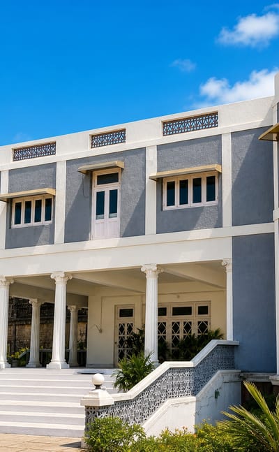 Grey-and-white colonial-era mansion with a columned portico and wide steps in Himatnagar, Gujarat.