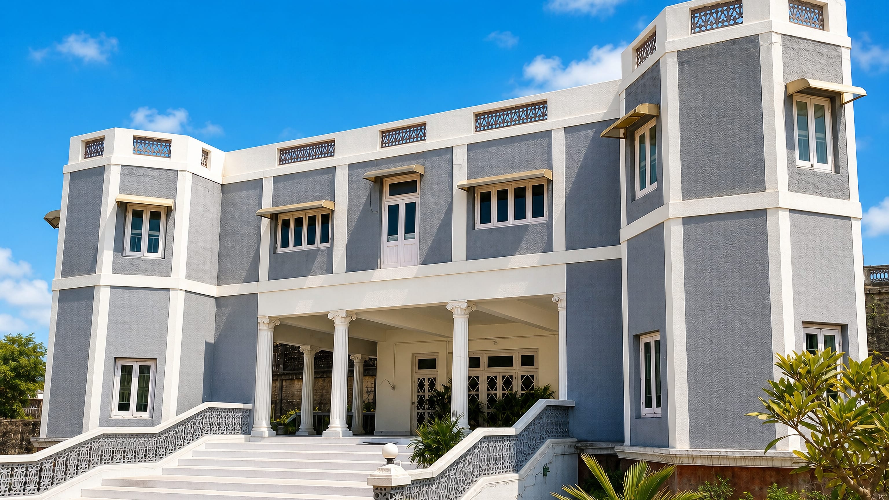 Grey-and-white colonial-era mansion with a columned portico and wide steps in Himatnagar, Gujarat.