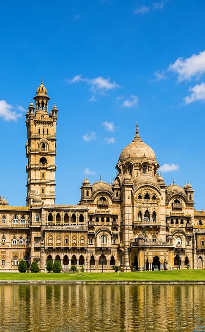 Lakshmi Vilas Palace in Vadodara, India, its Indo-Saracenic towers and domes reflected in a calm lake.