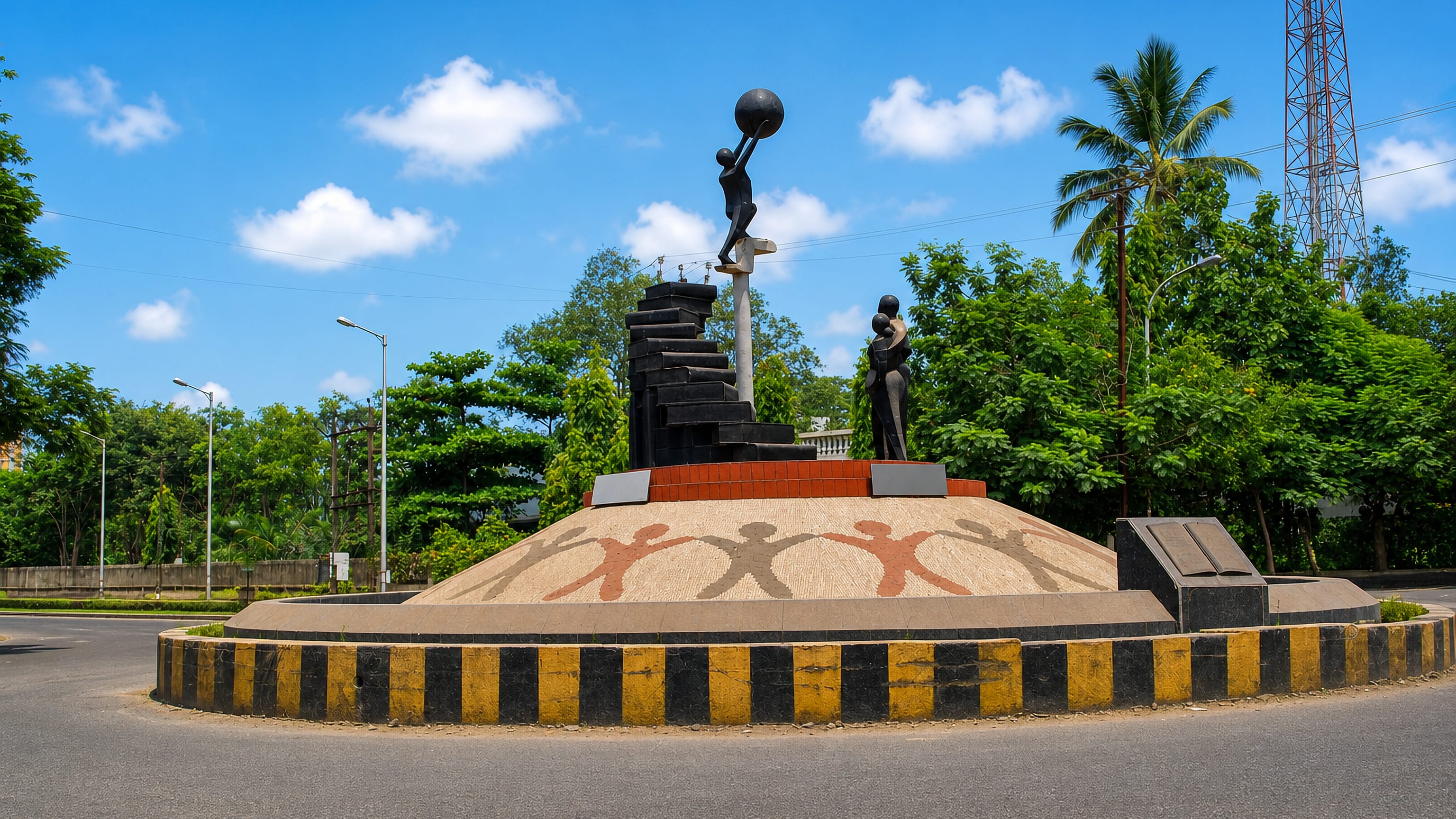 Abstract black figure sculptures on a landscaped traffic roundabout in Vapi, Gujarat, framed by palm trees
