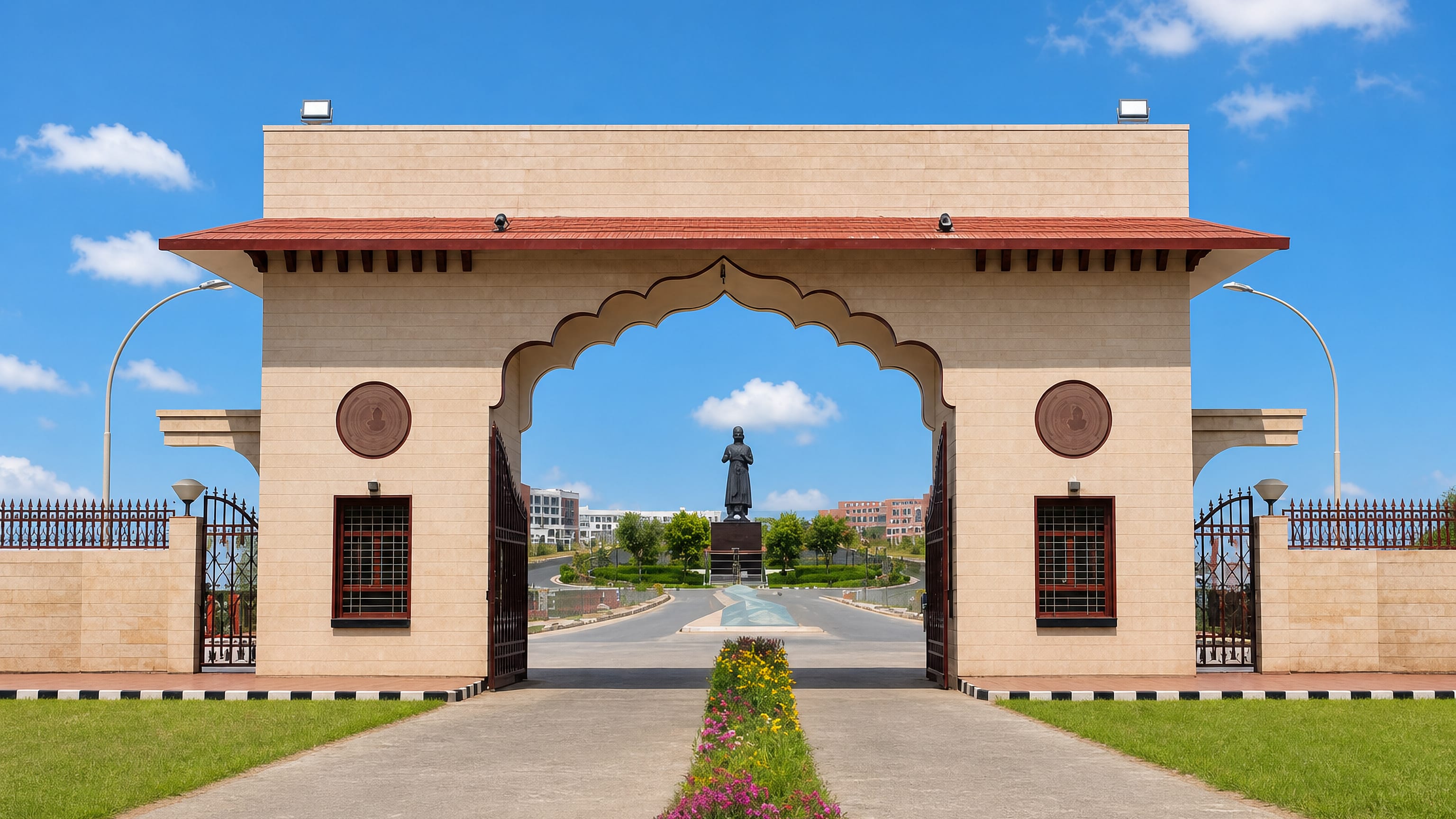 Ornate stone entrance gate and a bronze statue at a university campus in Rohtak, Haryana.