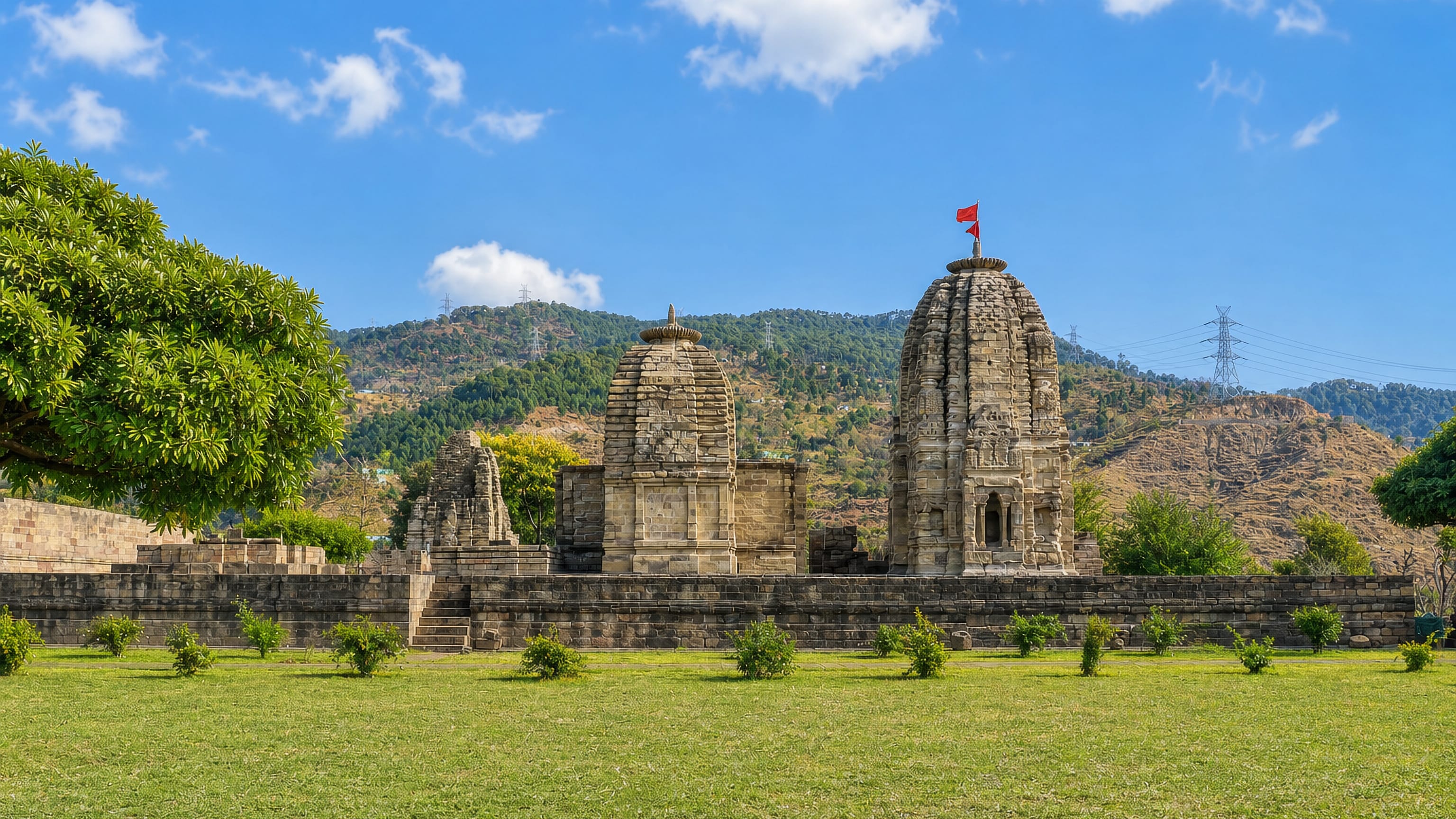 Ancient stone shikhara temples on a walled lawn below forested hills near Udhampur, Jammu and Kashmir