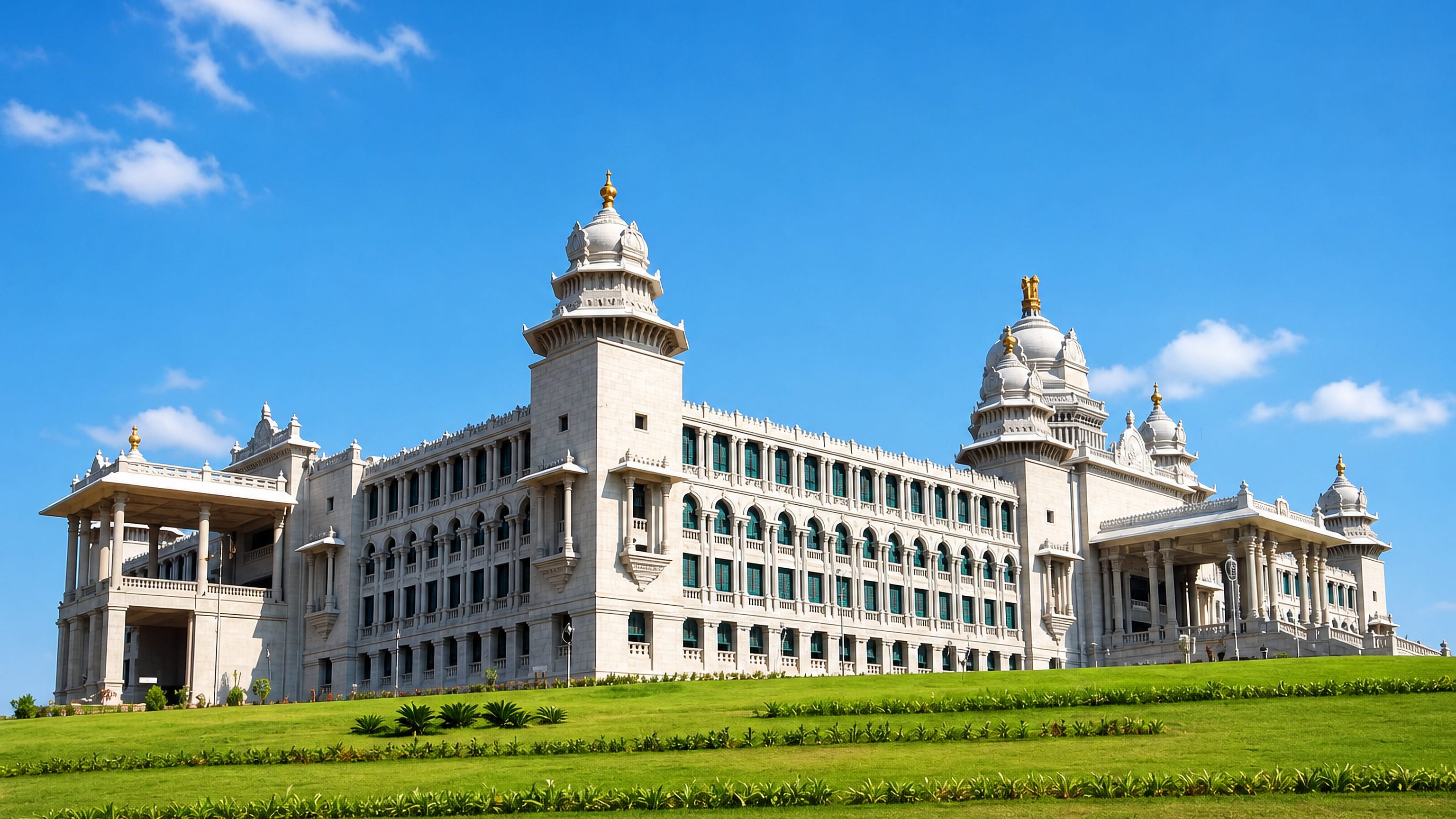 The white granite Suvarna Vidhana Soudha in Belagavi, its domes and arcaded facade rising above manicured lawns