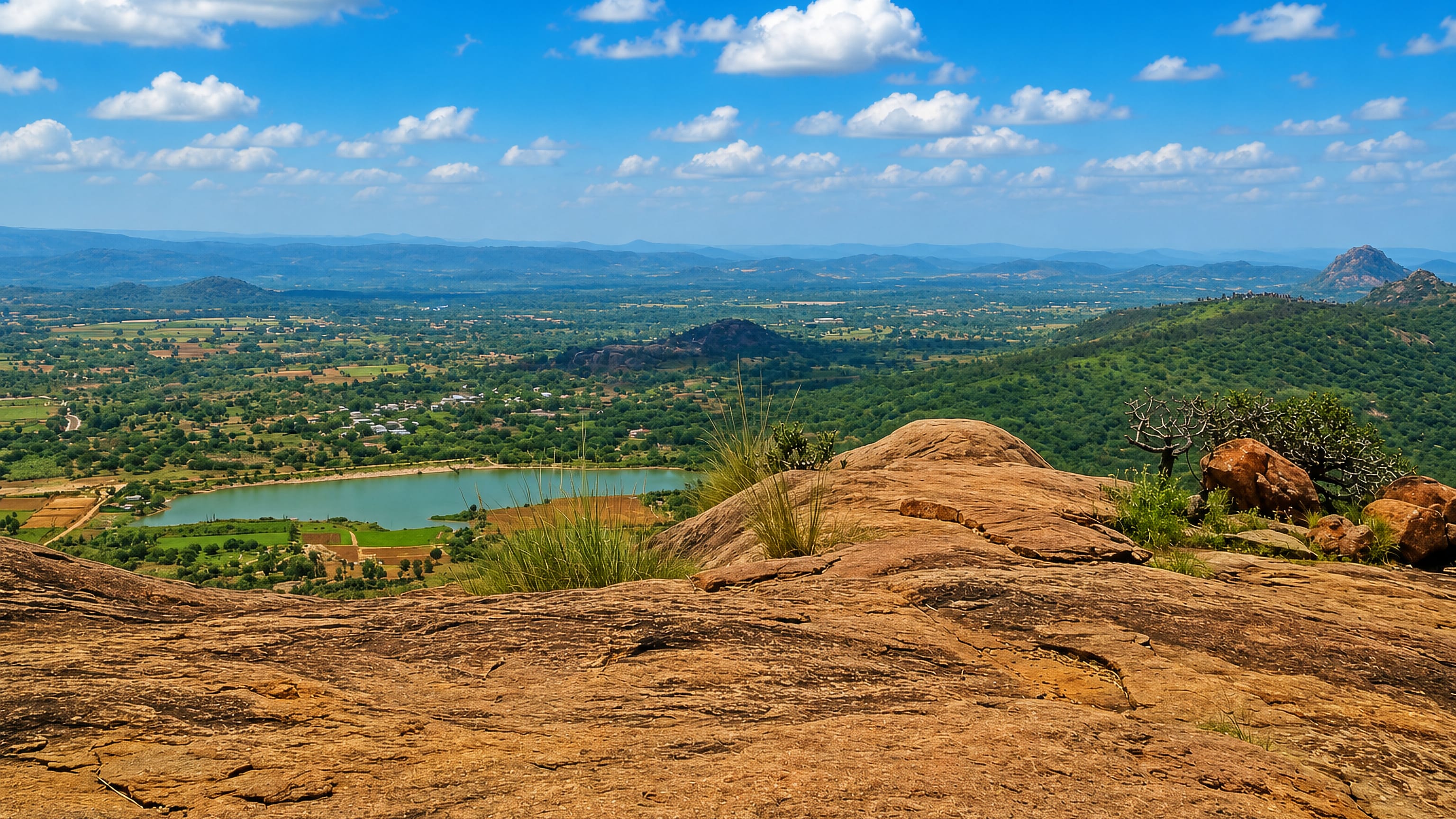 Granite outcrop above farmland, a reservoir and distant hills near Kanakapura, Karnataka, India.