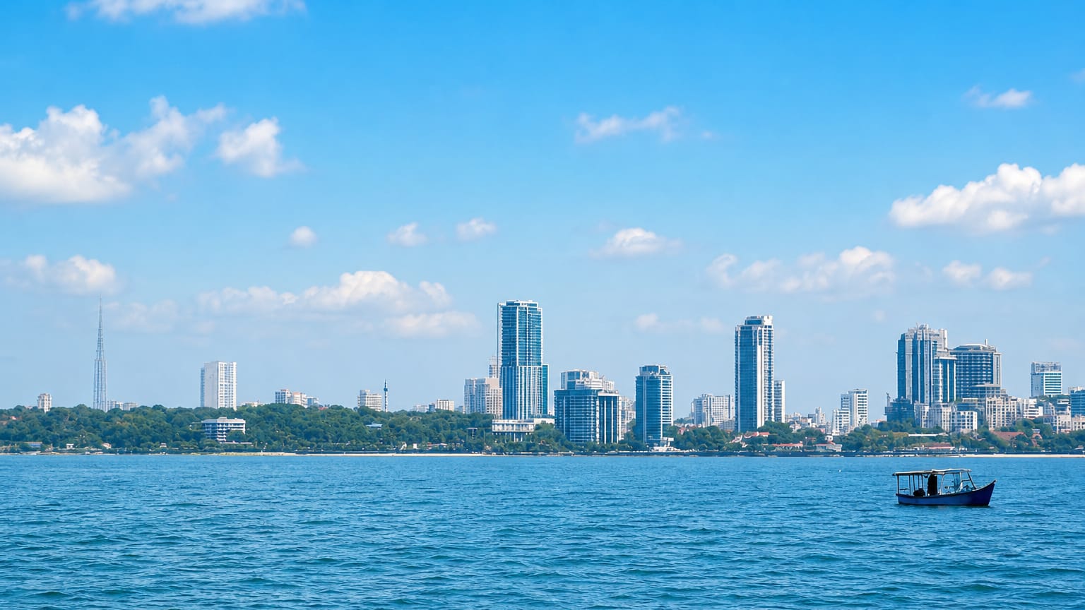 Cluster of glass high-rise towers along a waterfront at Kozhikode, seen across calm blue water.