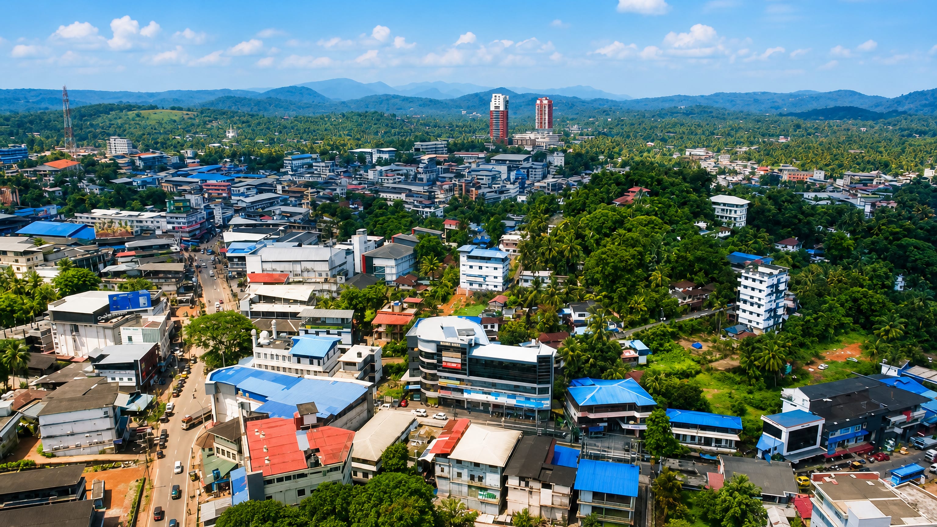Aerial view of Manjeri, Kerala, blue-roofed buildings and palms spreading below the Western Ghats
