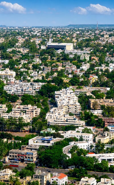 Aerial view of the low-rise urban sprawl of Aurangabad, India, with cream buildings, greenery and distant hills