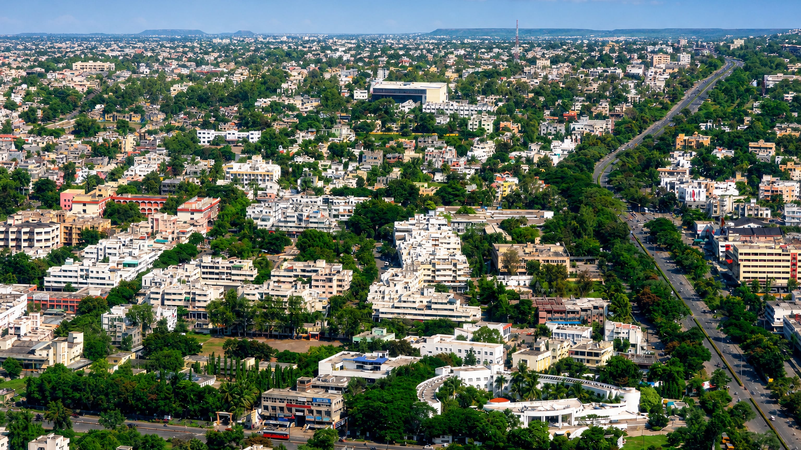 Aerial view of the low-rise urban sprawl of Aurangabad, India, with cream buildings, greenery and distant hills