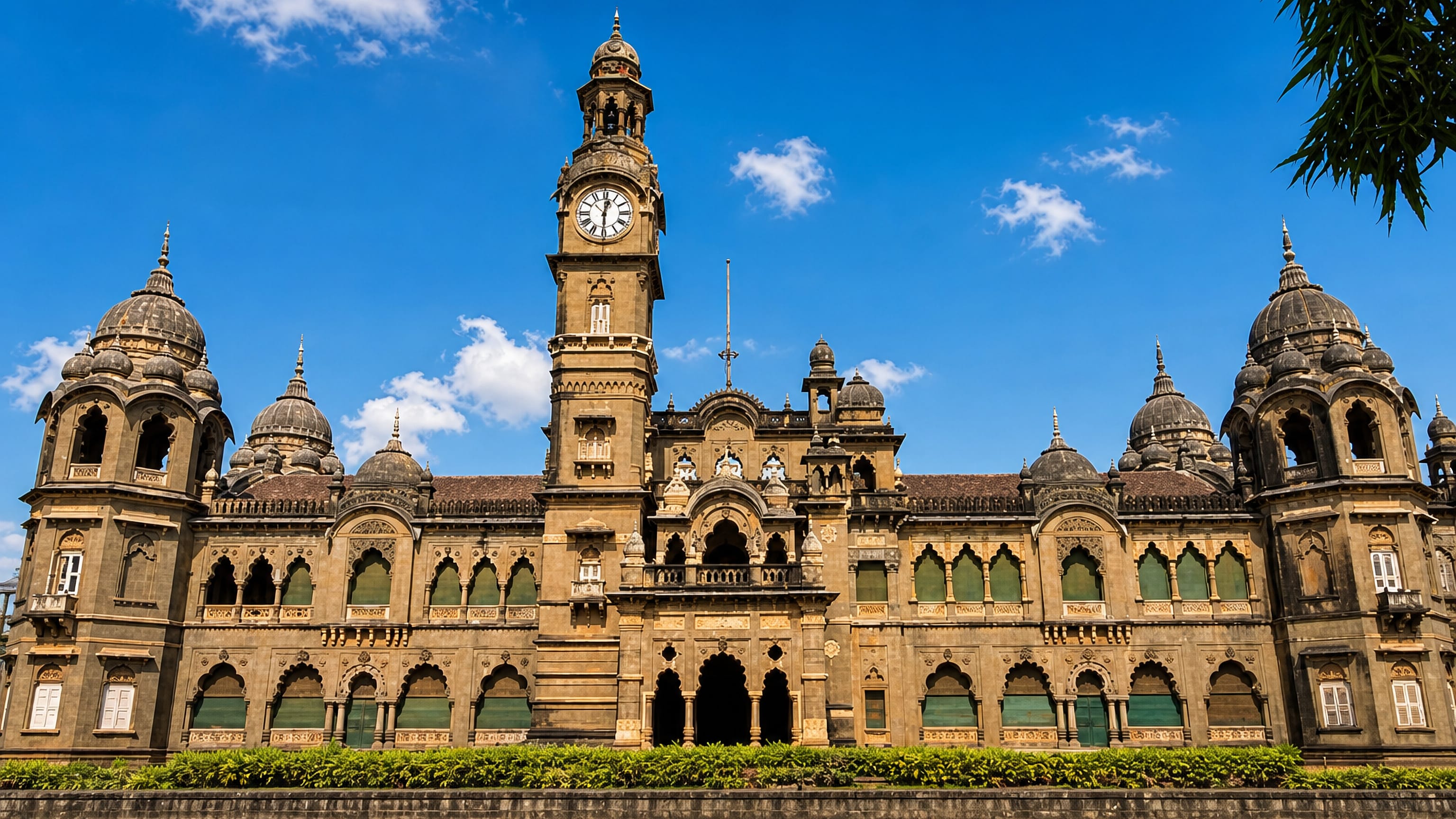 Kolhapur's New Palace, an Indo-Saracenic sandstone building with domed turrets and a clock tower above its lake.