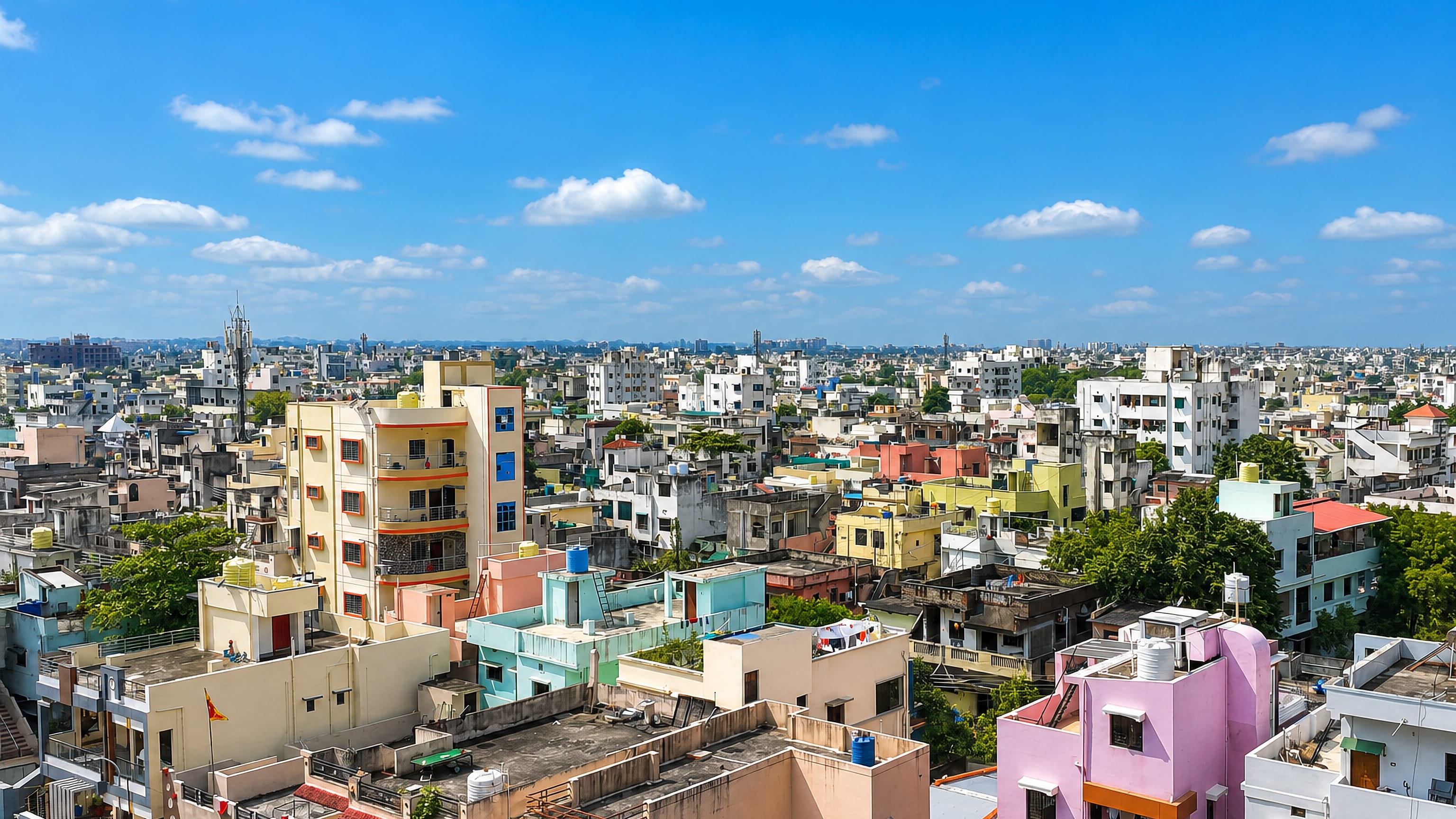 Rooftops of densely packed, colourful mid-rise buildings across Nagpur under a clear blue sky.