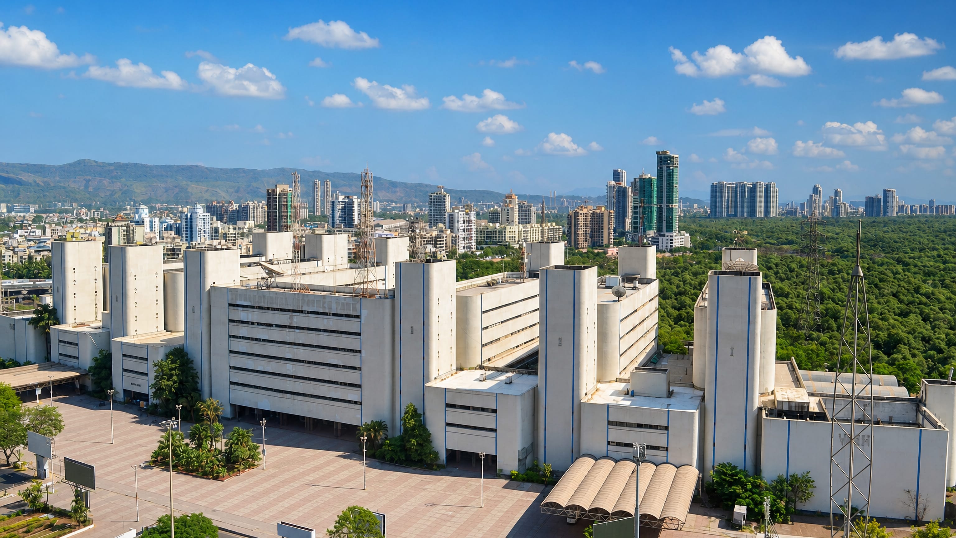 Concrete market complex with high-rise towers, forest belt and hills behind at Navi Mumbai, India.
