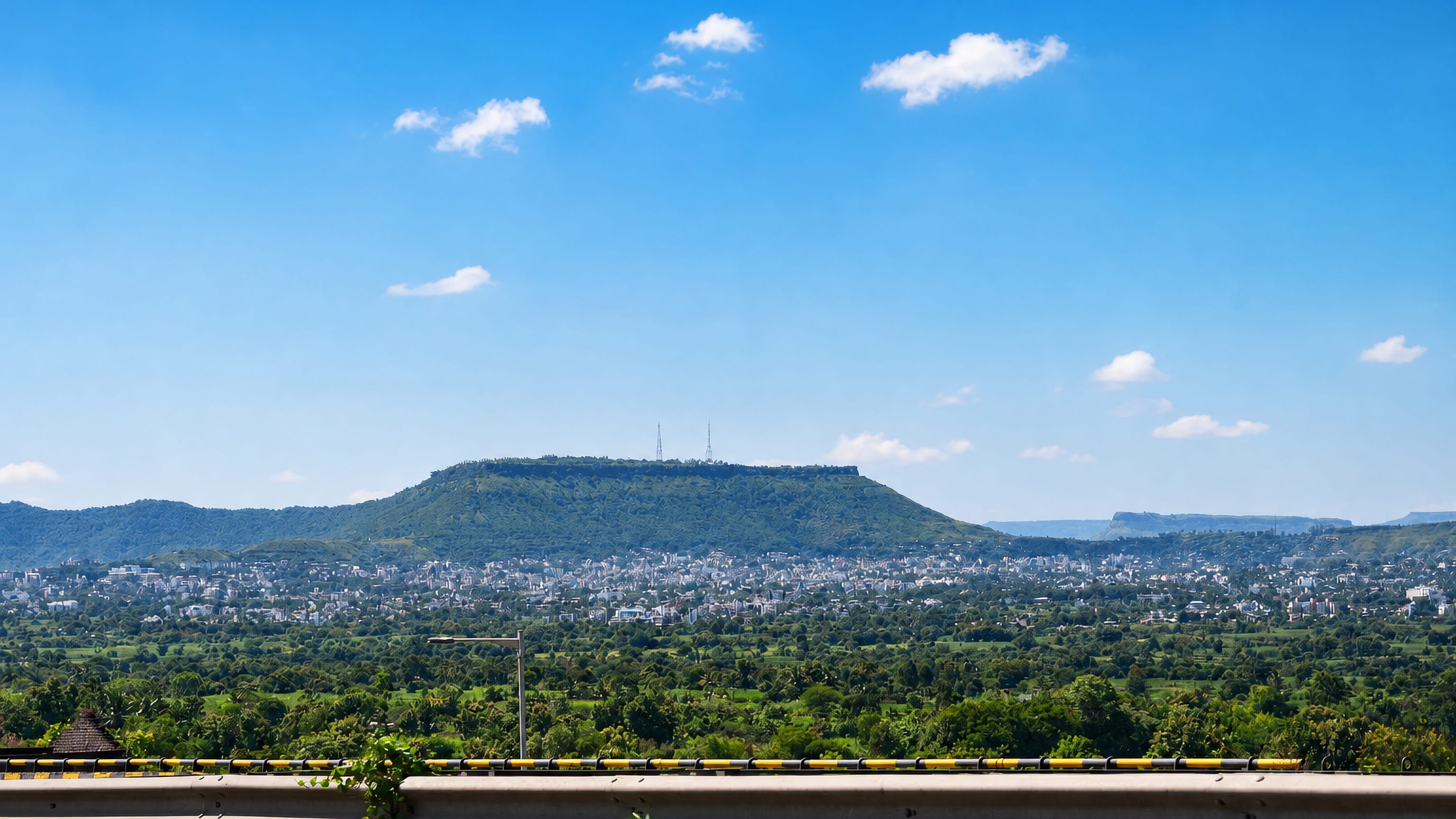Satara spreading below the flat-topped Ajinkyatara fort hill in Maharashtra, seen from a highway viewpoint.