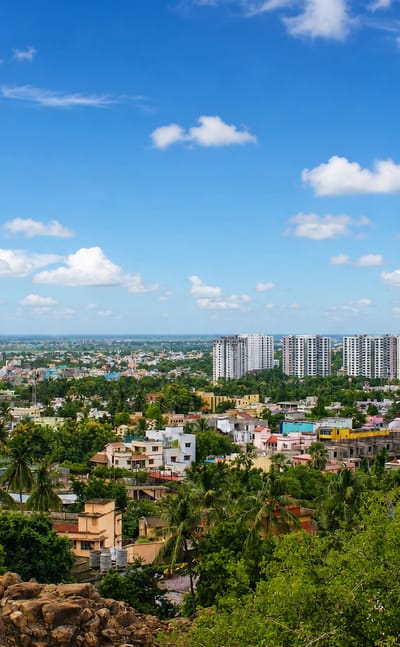 Green cityscape of Bhubaneswar with apartment towers and low houses seen from a rocky hill in Odisha.