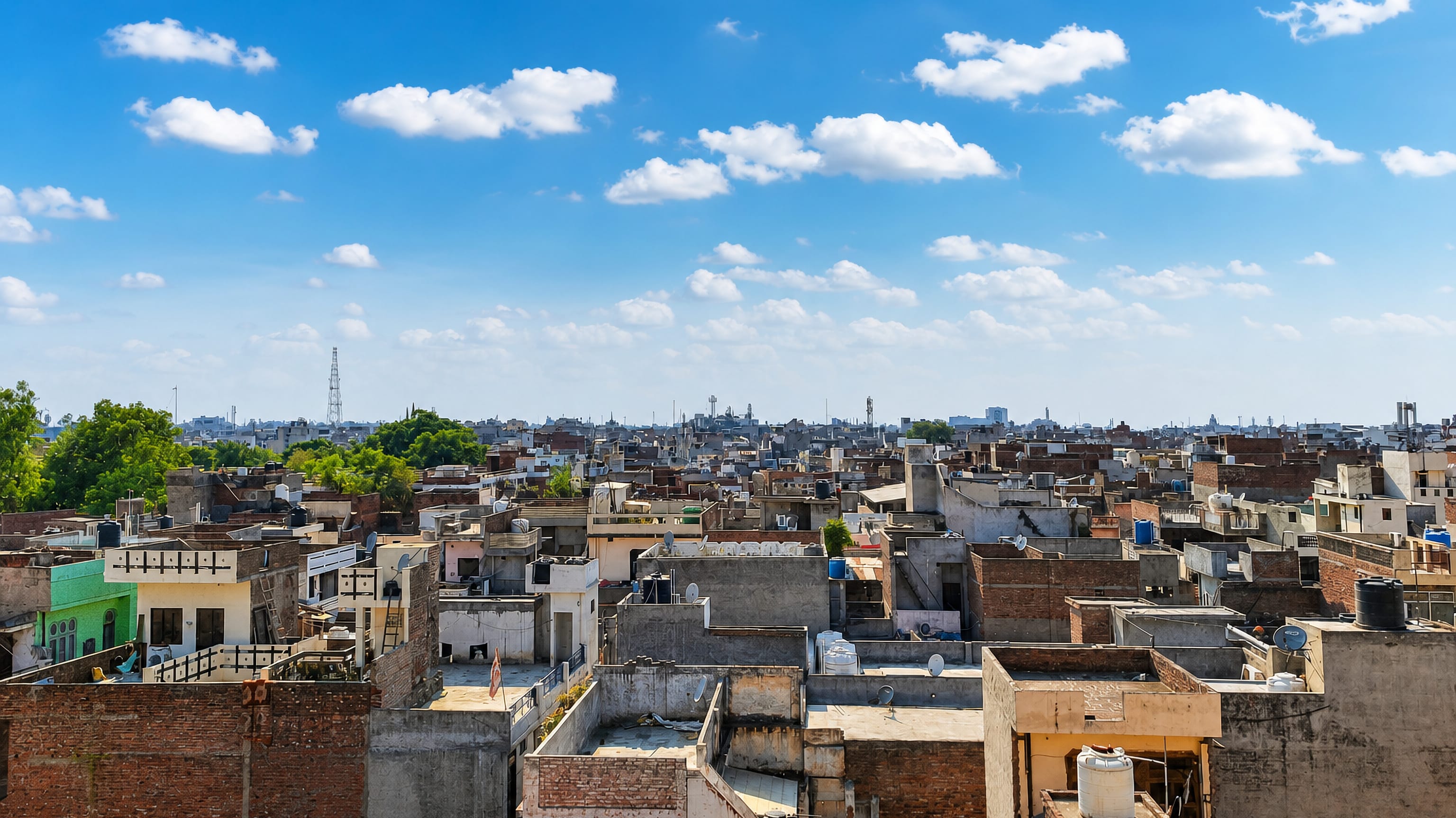 Dense rooftops with water tanks and satellite dishes stretch to the horizon across Ludhiana, Punjab.