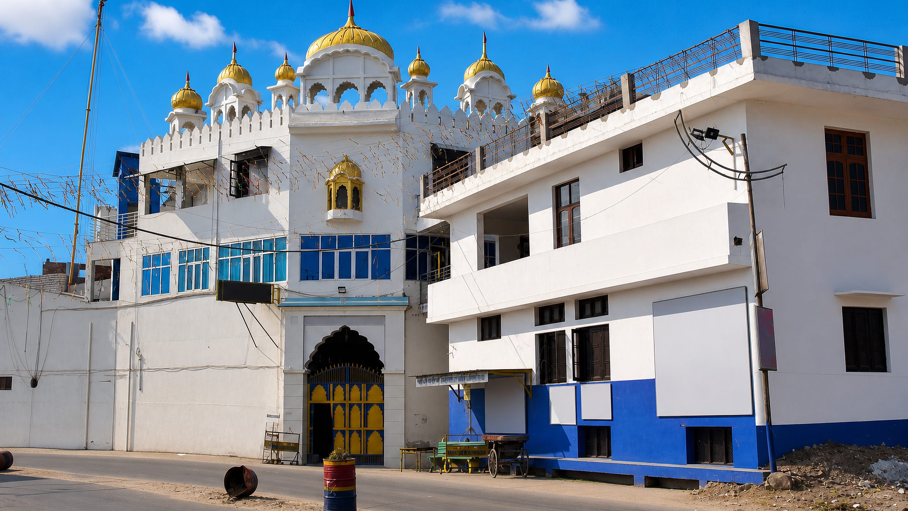White shrine with gold onion domes beside a quiet street in Māler Kotla, Punjab, India.