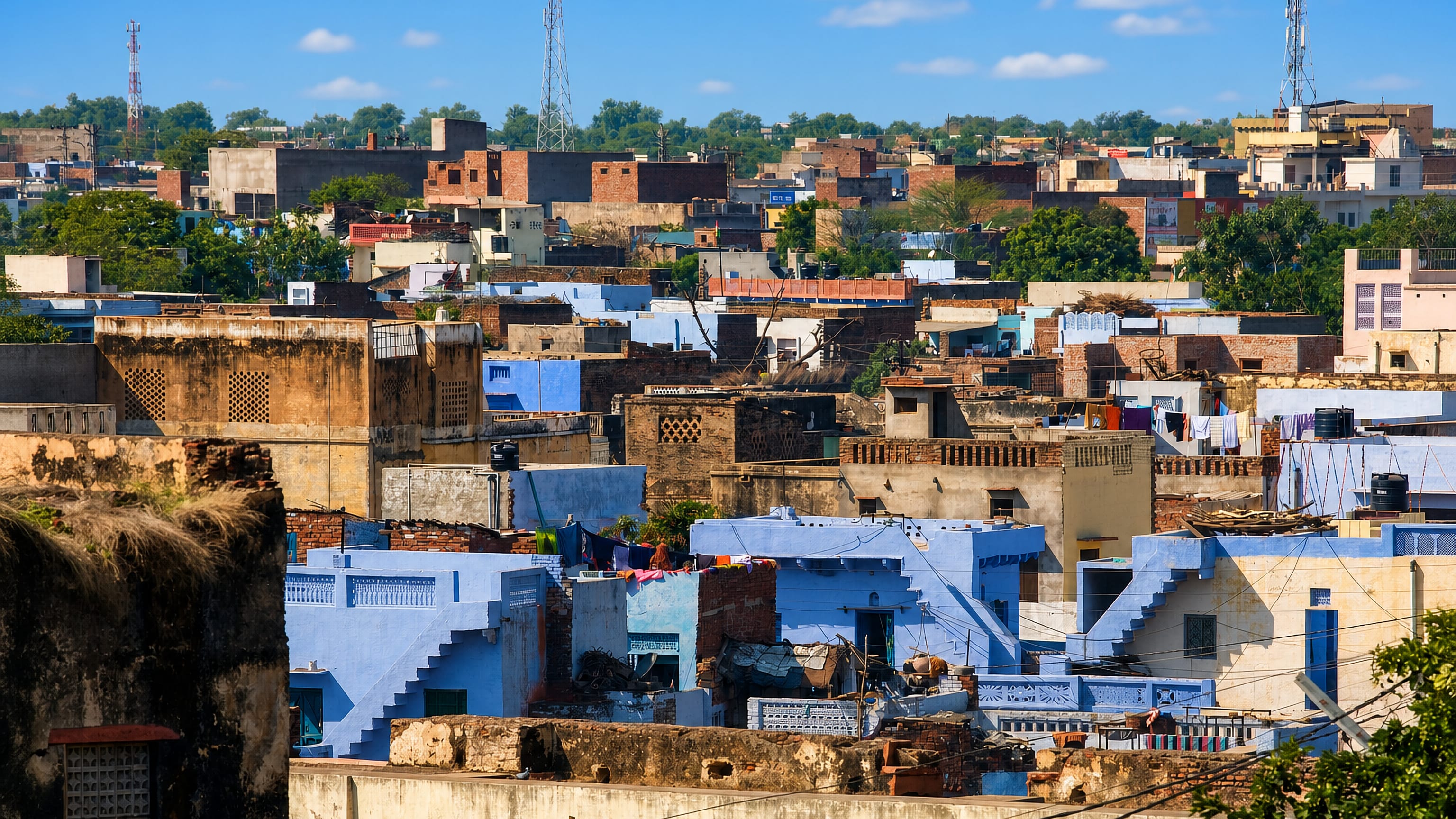 Rooftops of Bharatpur, India, with blue-washed and brick houses packed together under a clear sky.