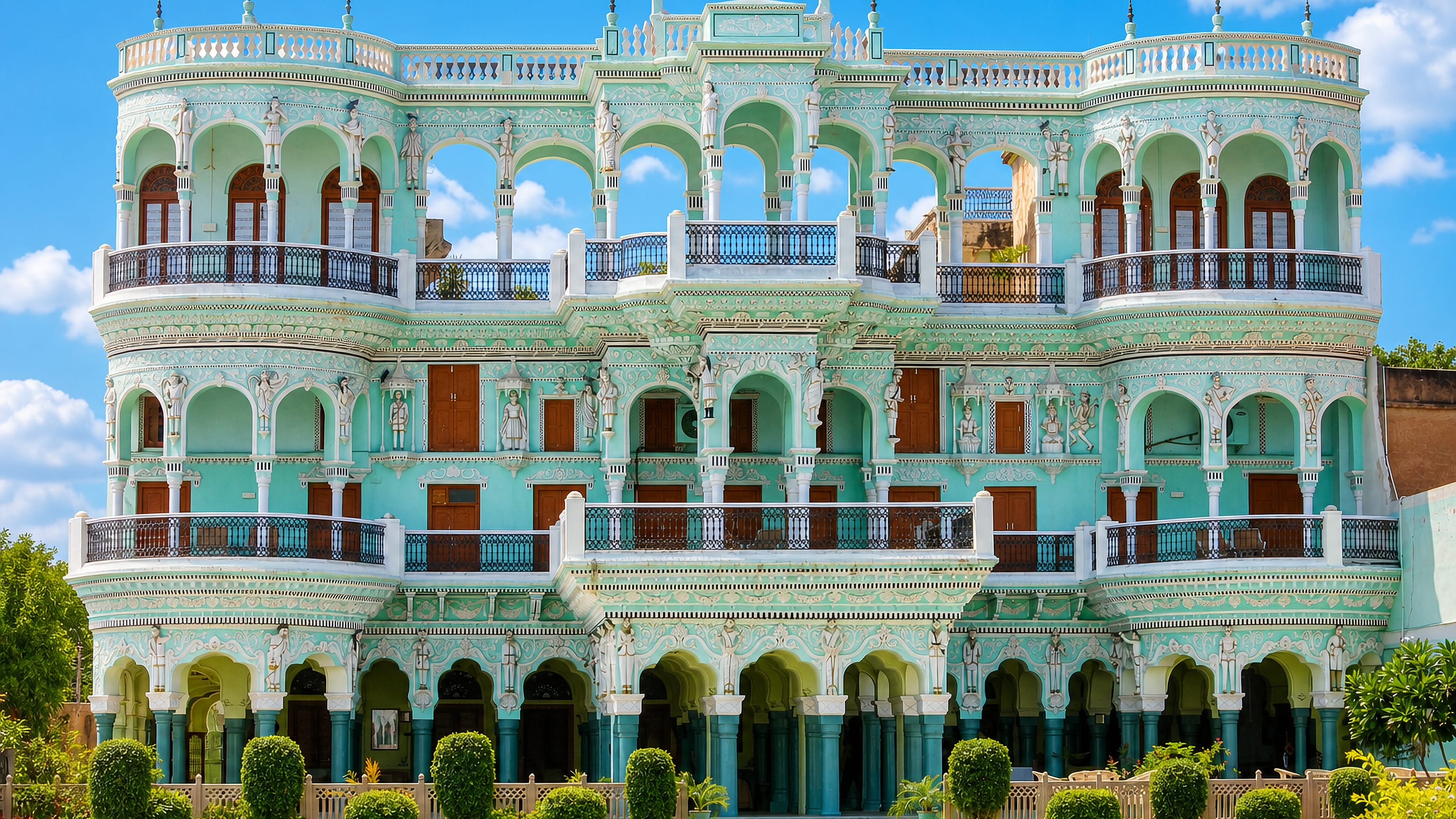 An ornate mint-green Shekhawati haveli with frescoed arches and statues in Churu, Rajasthan.
