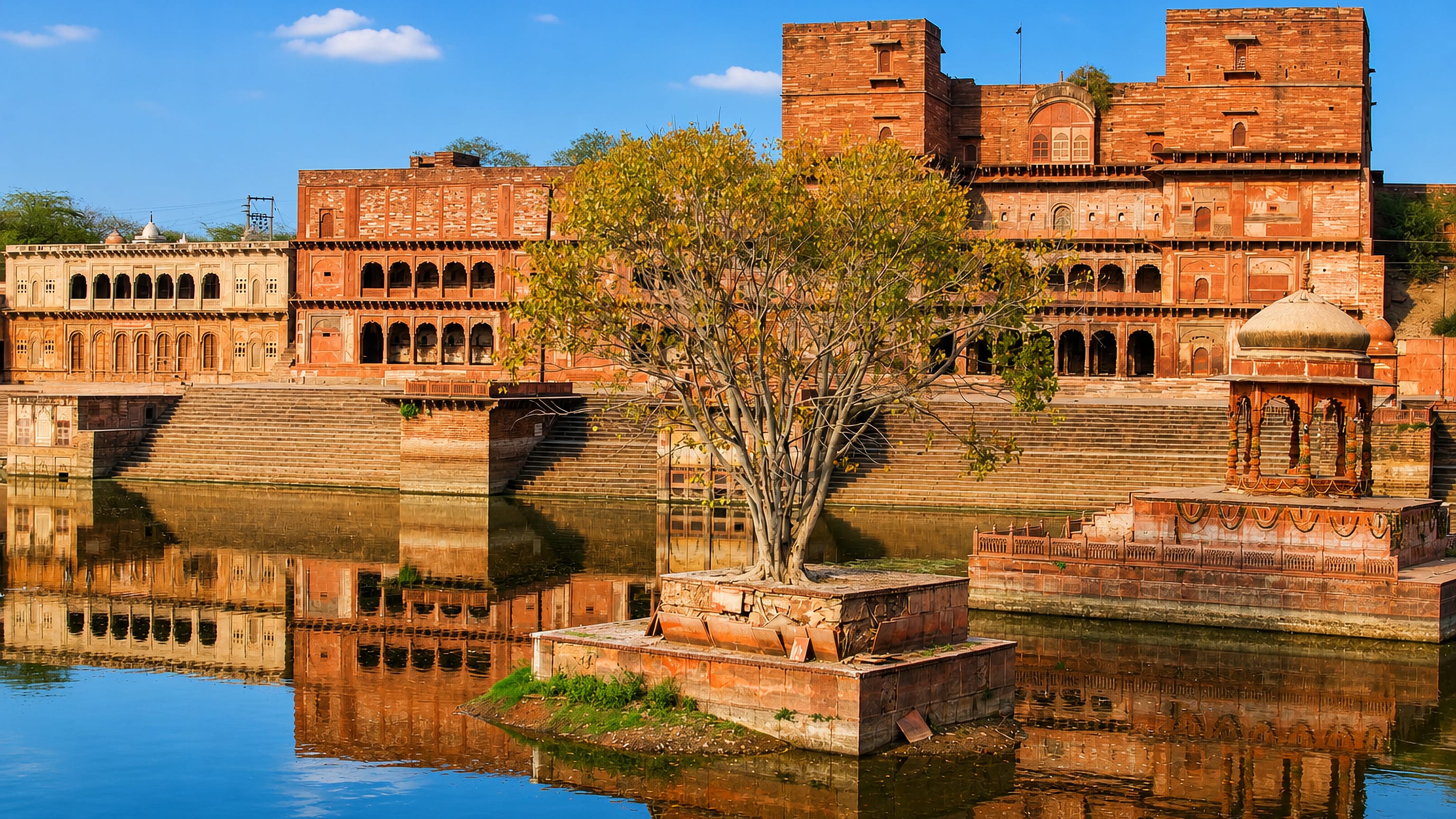 Red sandstone palace arcades, ghats and a domed chhatri reflected in still water at Dhaulpur, Rajasthan.