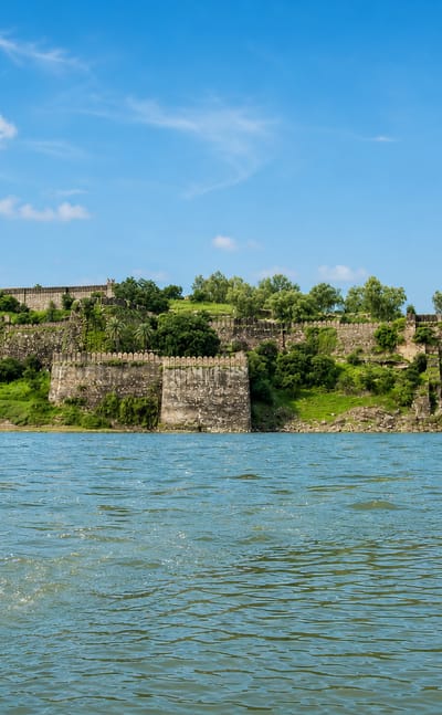 Stone fort ramparts on a wooded ridge above the river at Jhalawar, Rajasthan.