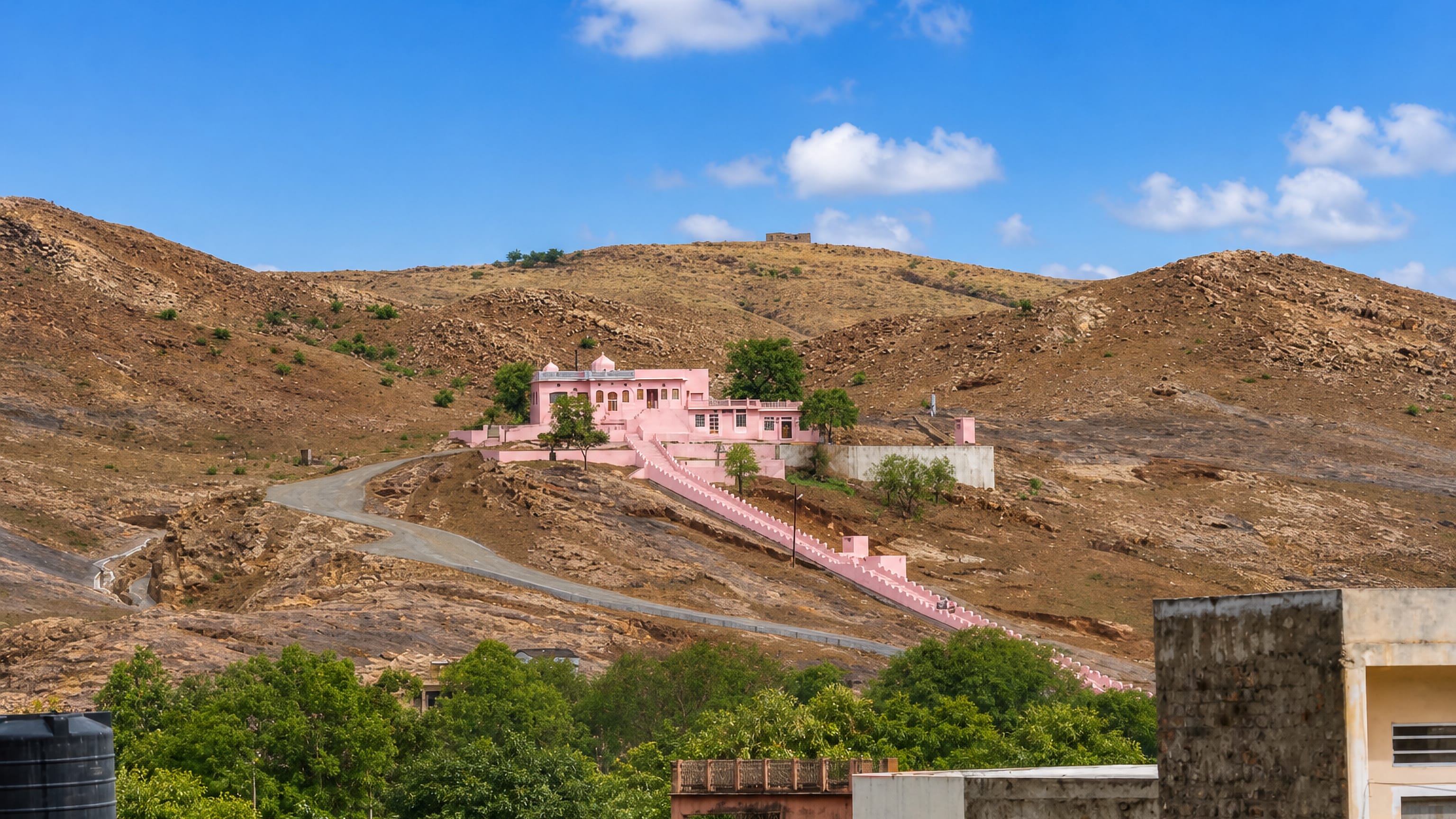 Pink hilltop temple on arid Aravalli hills above rooftops in Sawai Madhopur, Rajasthan