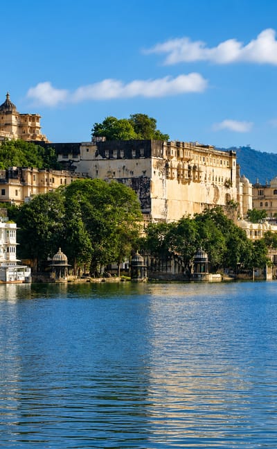 Udaipur's City Palace complex rising above Lake Pichola under a blue sky
