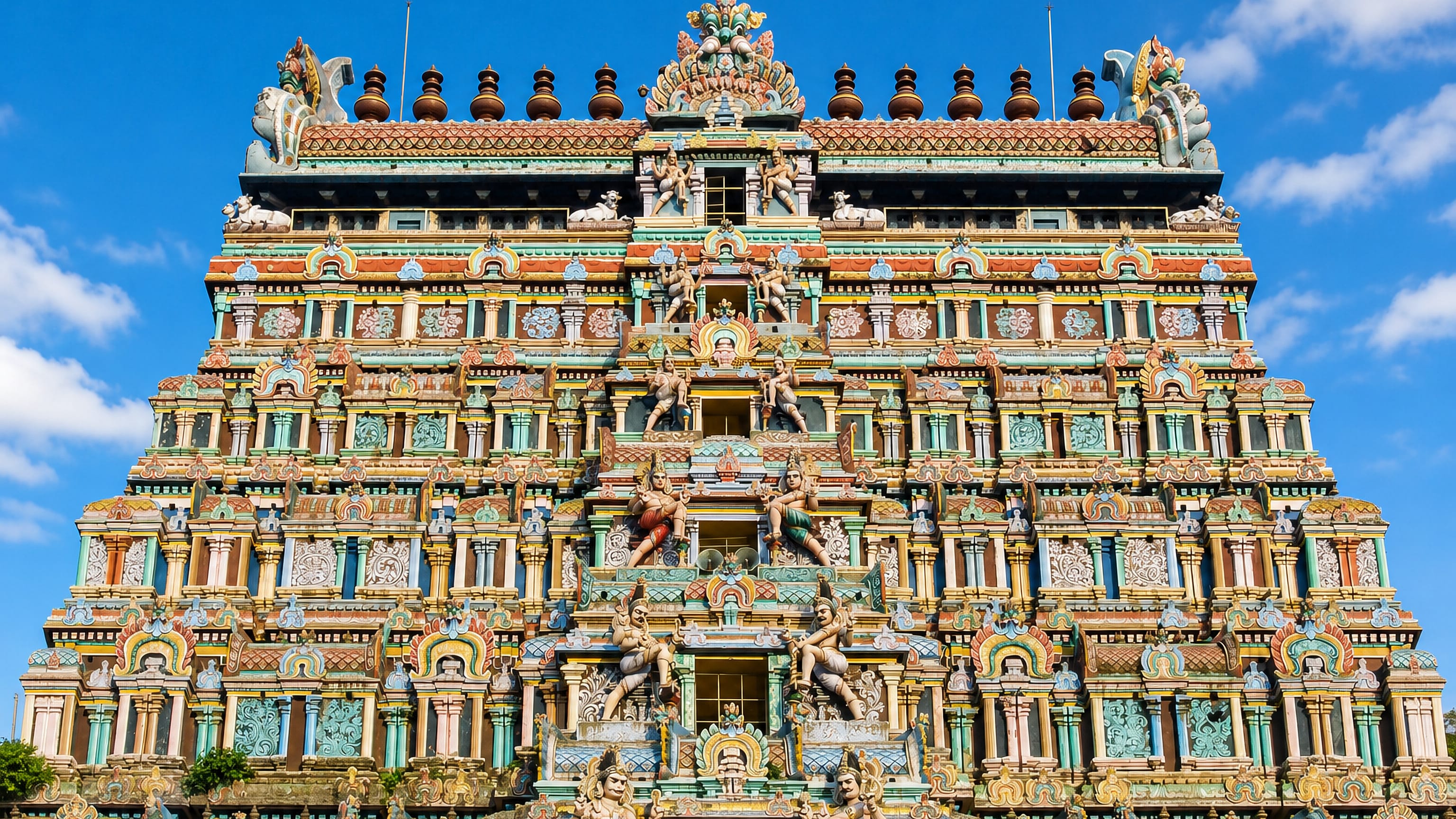 Brightly painted Dravidian gopuram tower of Chidambaram's Nataraja temple in Tamil Nadu, rising above water.