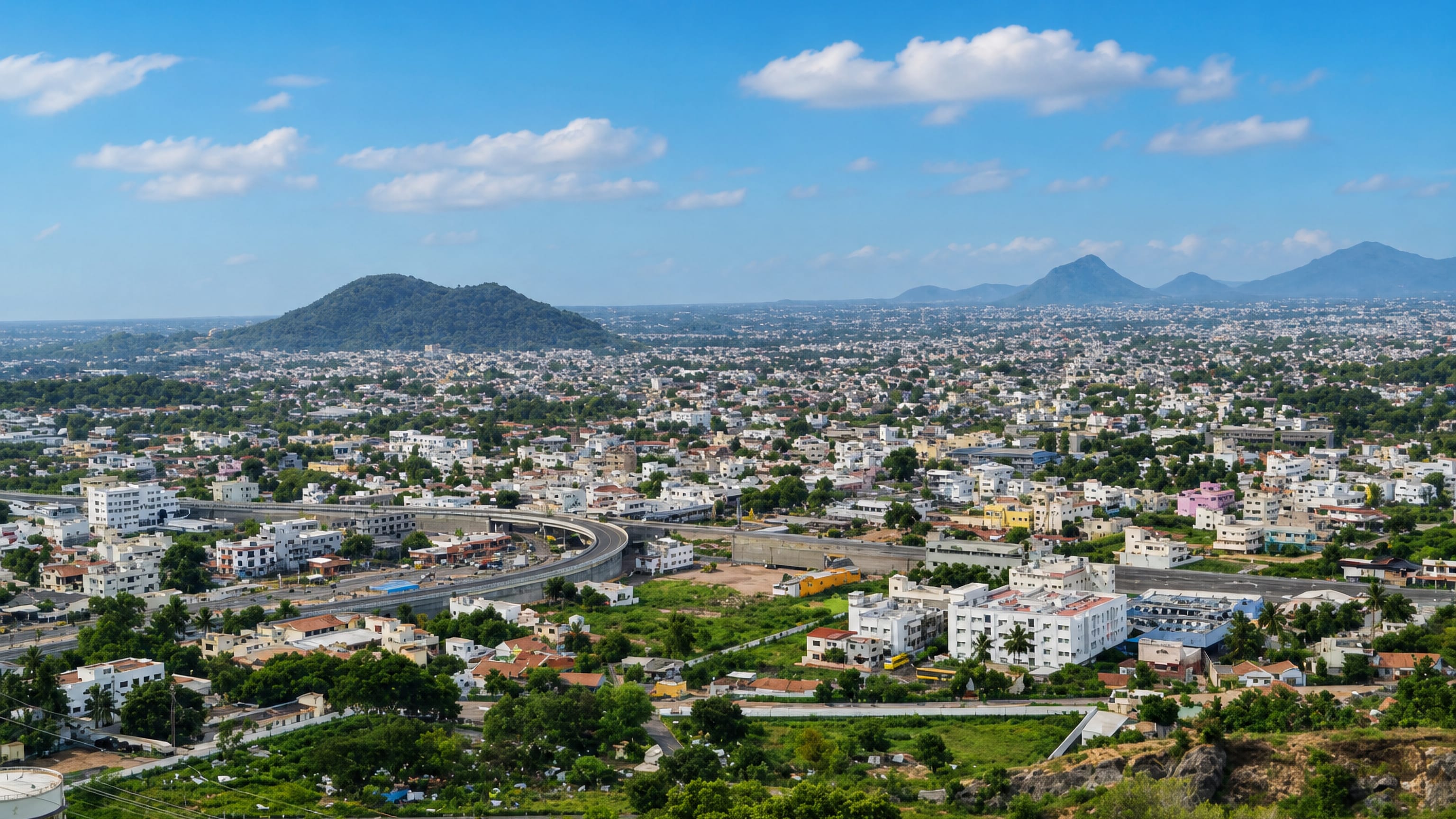 Hilltop panorama over Salem, Tamil Nadu, its low-rise sprawl and curving flyover ringed by green hills