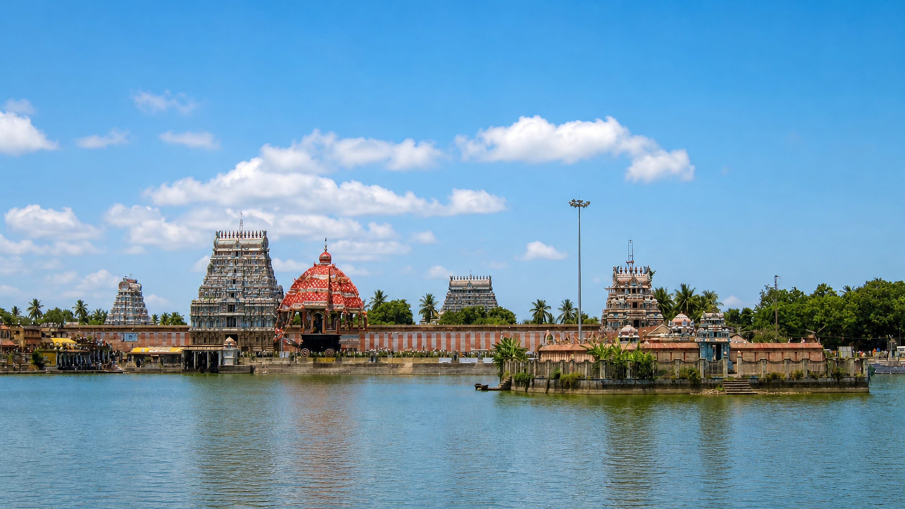 Gopurams and a red temple chariot reflected in the temple tank at Thiruvarur, Tamil Nadu.