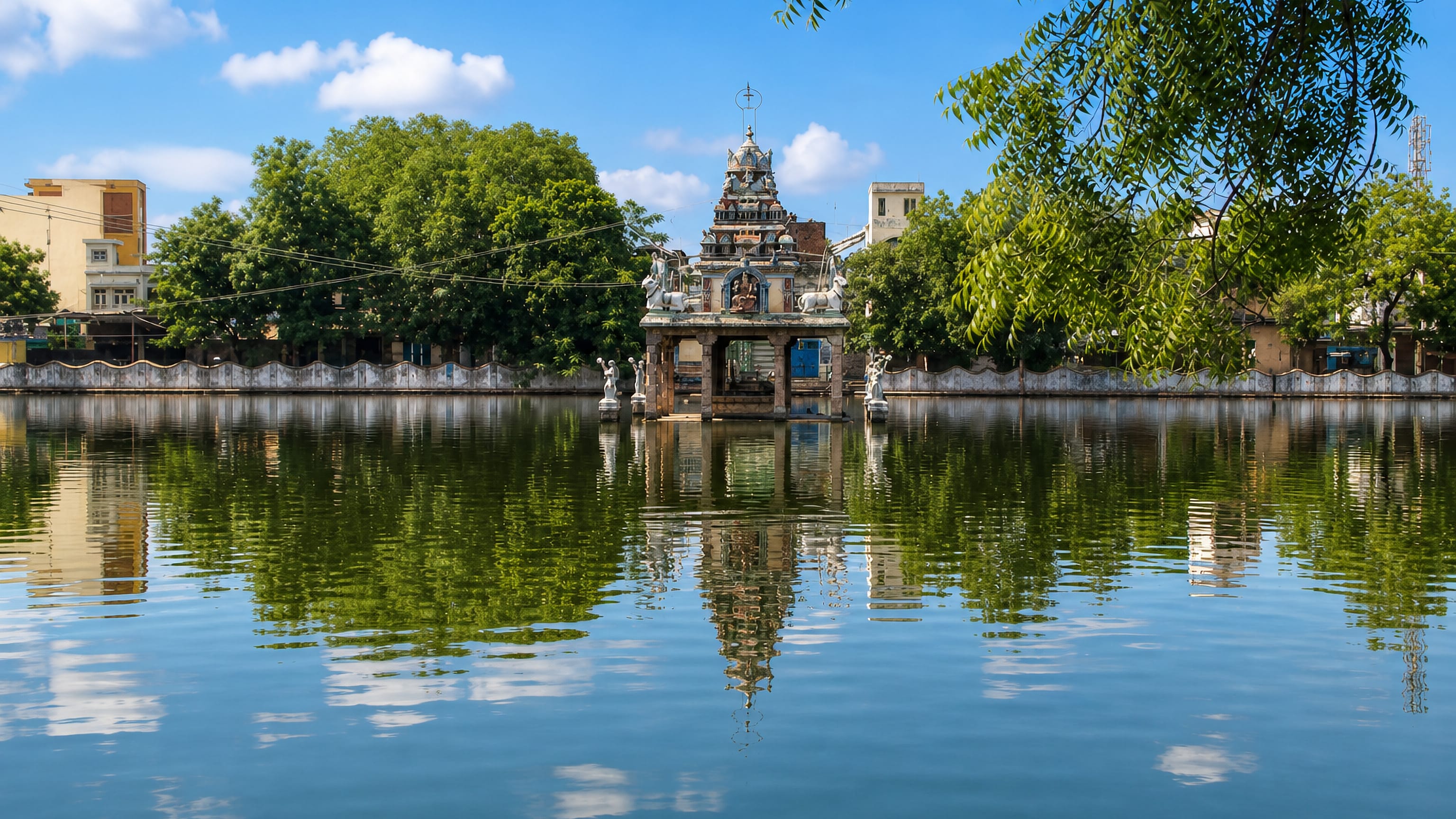 A temple tank in Virudunagar, Tamil Nadu, with a small shrine and gopuram mirrored in still water.