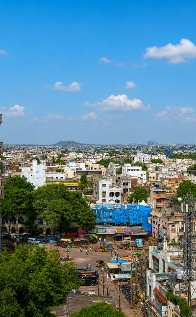 The Charminar's four minarets rising above Hyderabad's old city with the surrounding bazaar and skyline.