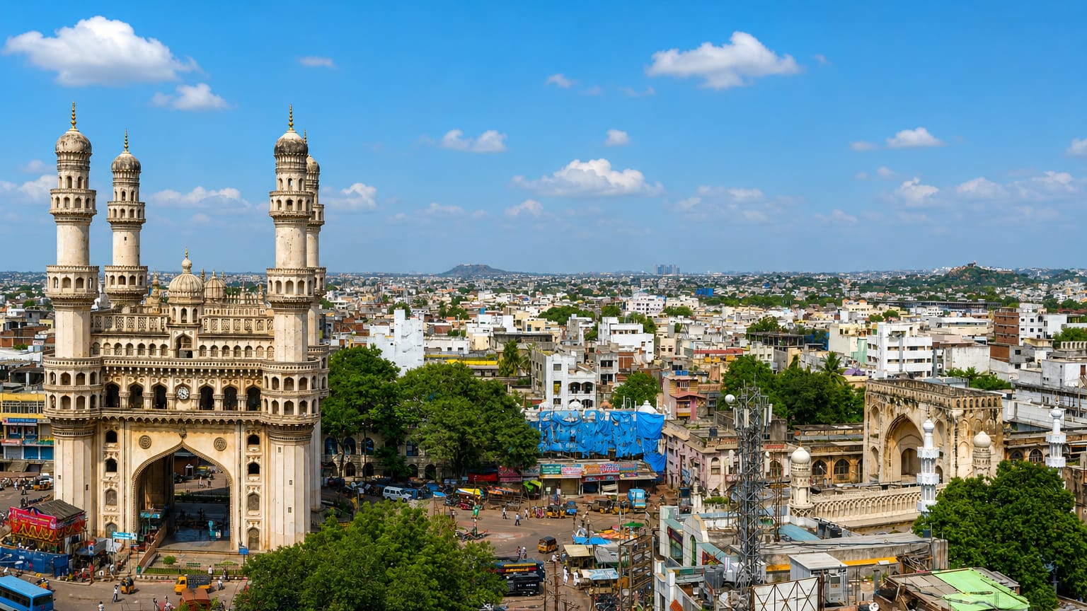 The Charminar's four minarets rising above Hyderabad's old city with the surrounding bazaar and skyline.
